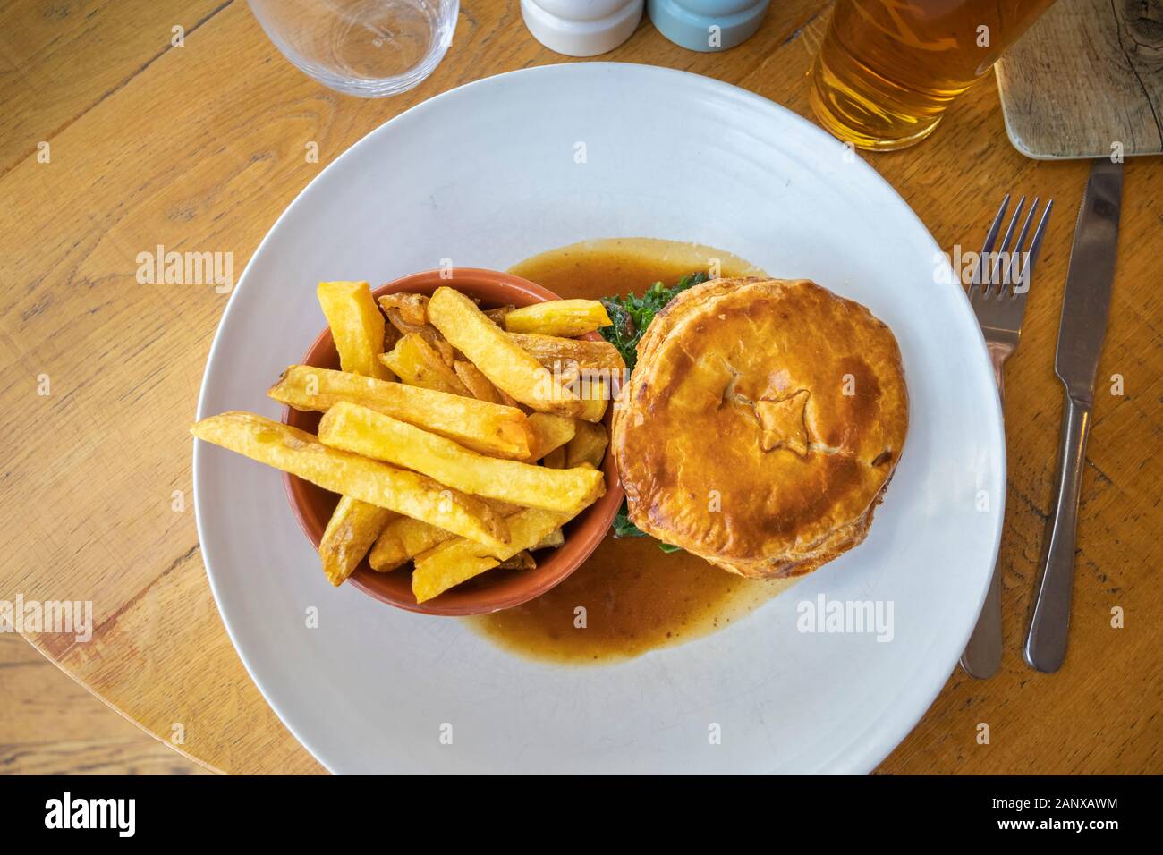 Copieux typique et savoureux repas au pub britannique : sex pâté à la viande en sauce servi avec un bol de golden fried chips chunky sur une plaque blanche chine Banque D'Images
