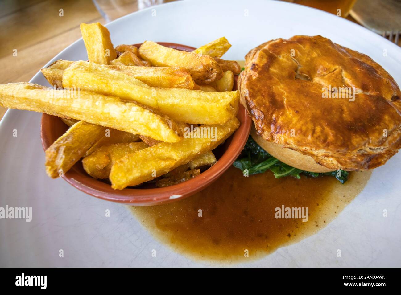 Copieux typique et savoureux repas au pub britannique : sex pâté à la viande en sauce servi avec un bol de golden fried chips chunky sur une plaque blanche chine Banque D'Images
