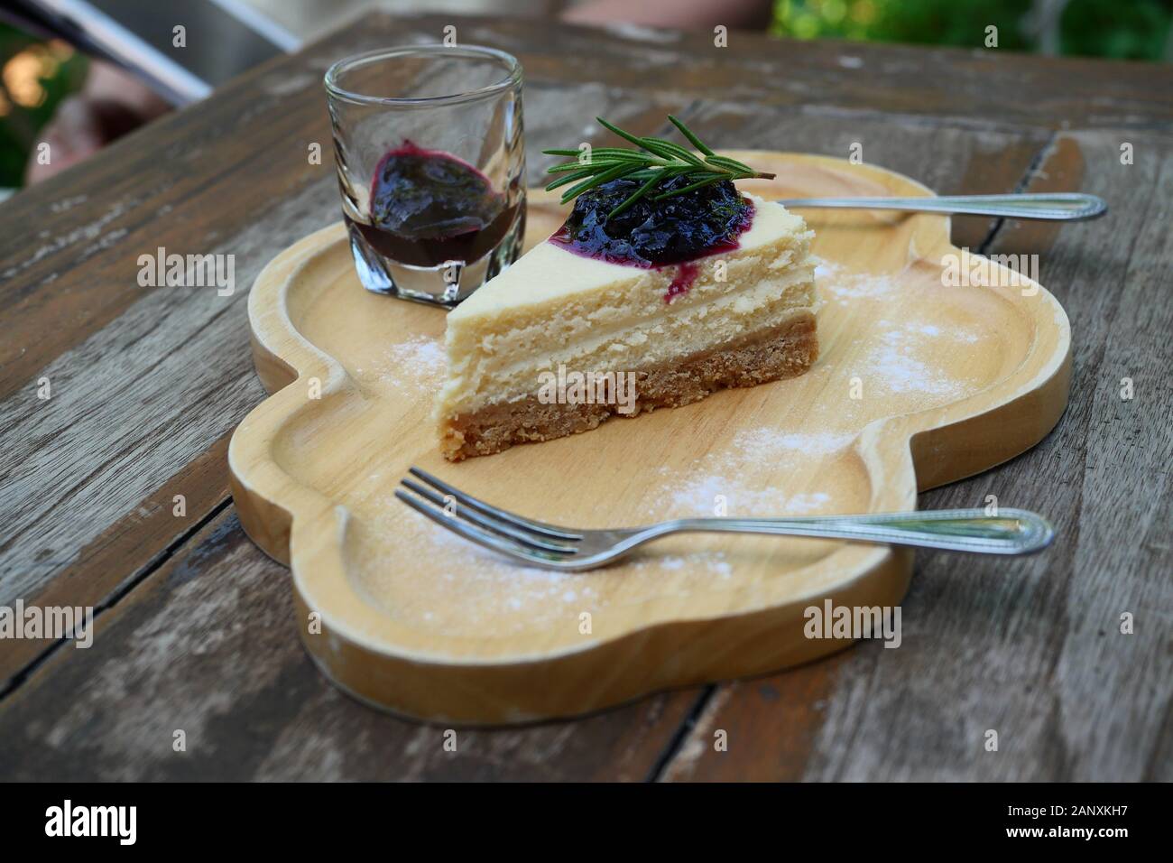 Le gâteau au fromage Camembert garnie de sirop de bleuet avec cuillère et fourchette sur une plaque de bois, un aliment sucré avec brown le tableau en arrière-plan Banque D'Images