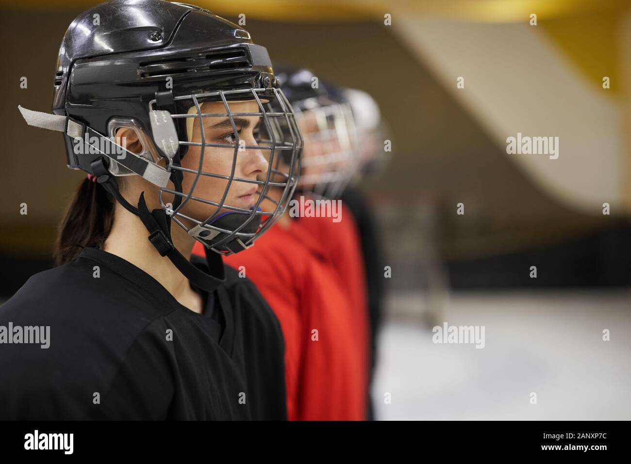 Vue de côté de l'équipe de hockey féminin de l'article en ligne avant le  match sur la patinoire, l'accent sur belle femme portant un casque de sport  en premier plan, copy space