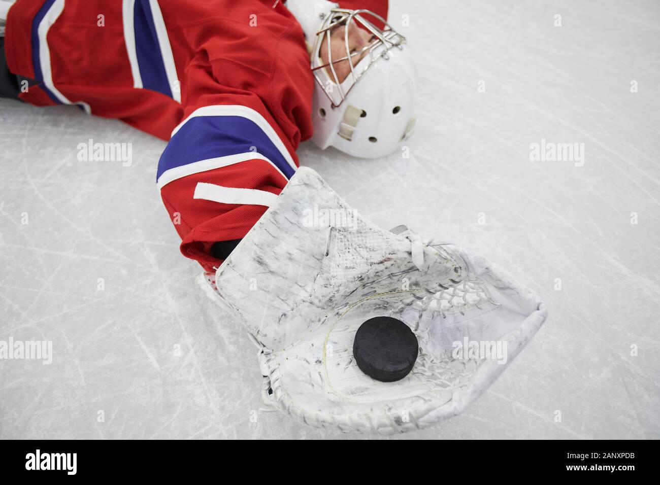 Close up de joueur de hockey féminin allongé sur la glace et holding pluck épuisé après la pratique, copy space Banque D'Images