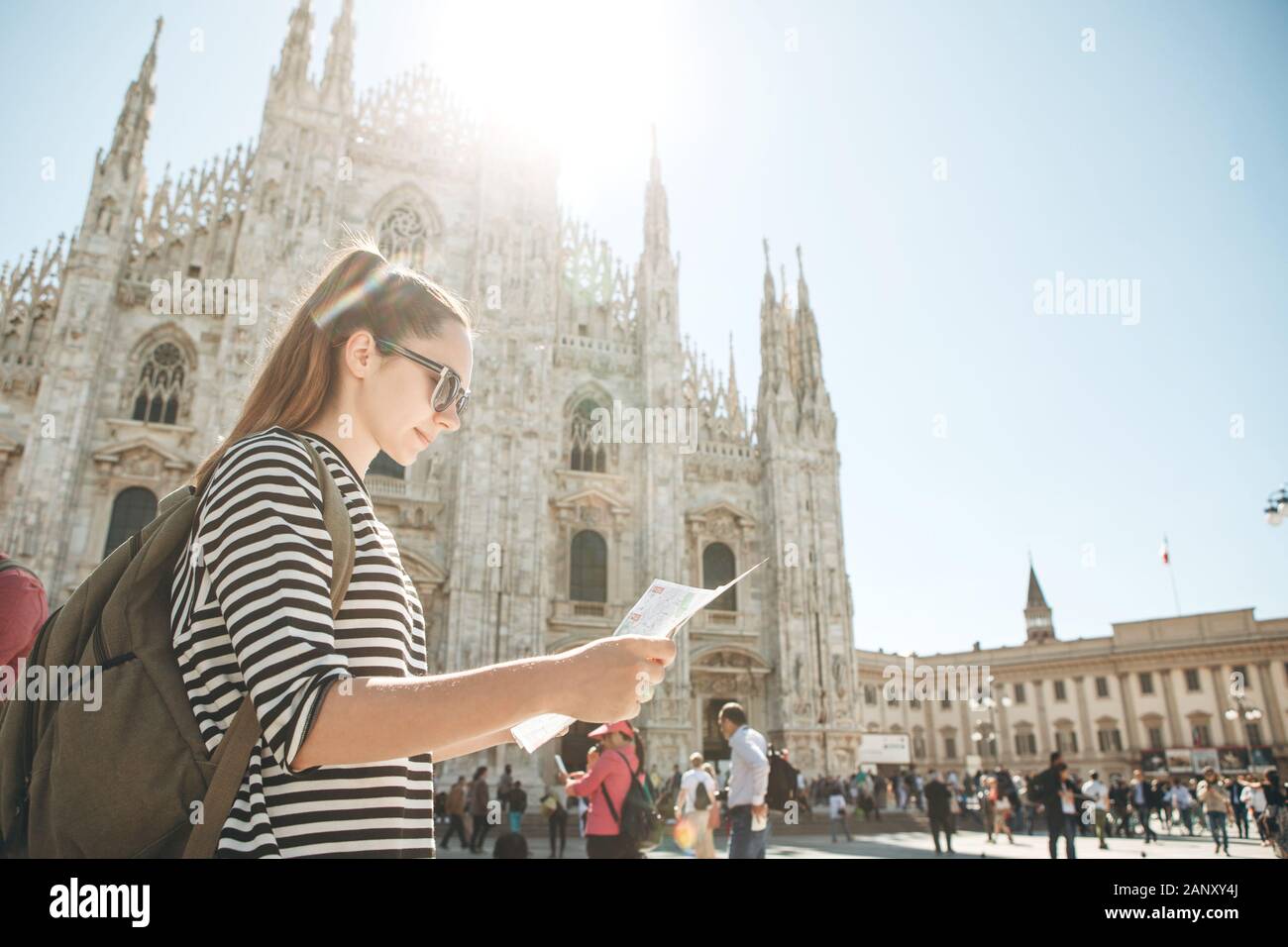 Girl touriste ou étudiant avec un sac à dos ressemble à la carte. Dans l'arrière-plan la cathédrale Duomo de Milan en Italie et méconnaissable. Banque D'Images