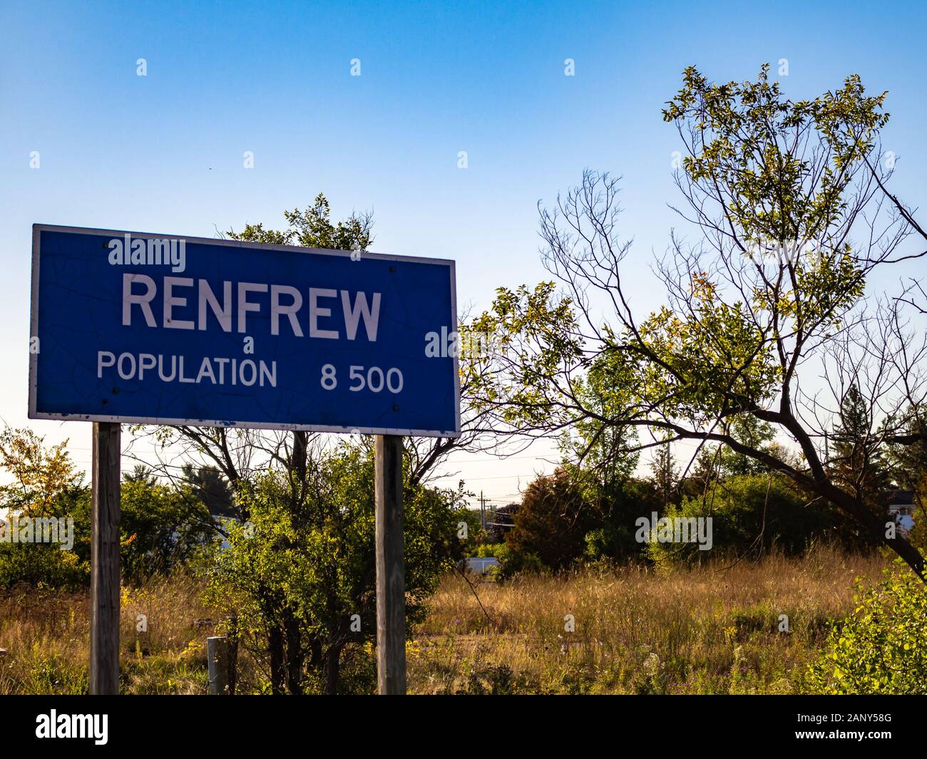 Un signe marquant les limites de la ville de Renfrew, Ontario affiche la ville, la population est estimée à 8 500 personnes en face de l'herbe, buissons et arbres Banque D'Images