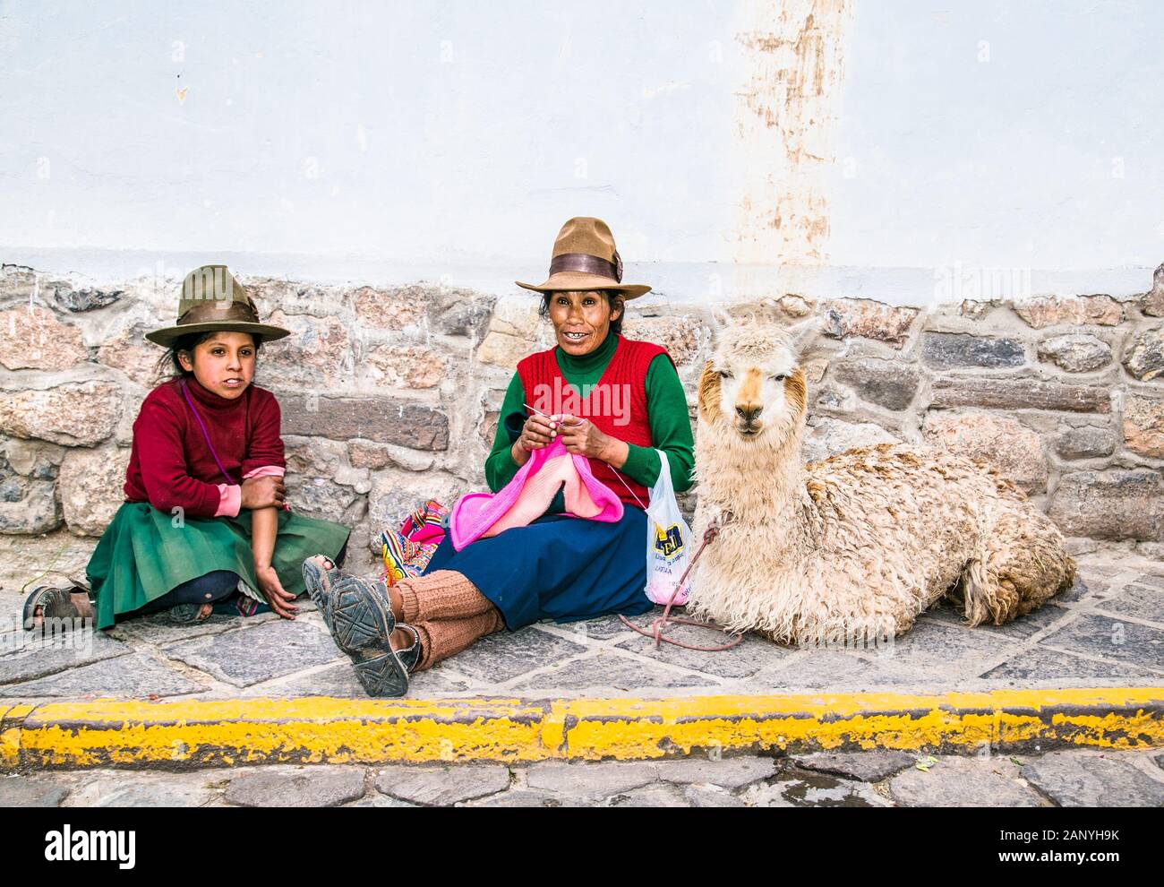 Cusco , Pérou- Jan 9, 2019 : vieille femme Quechua avec lama et yong girl knits à rue de Cusco. Le Pérou. Banque D'Images