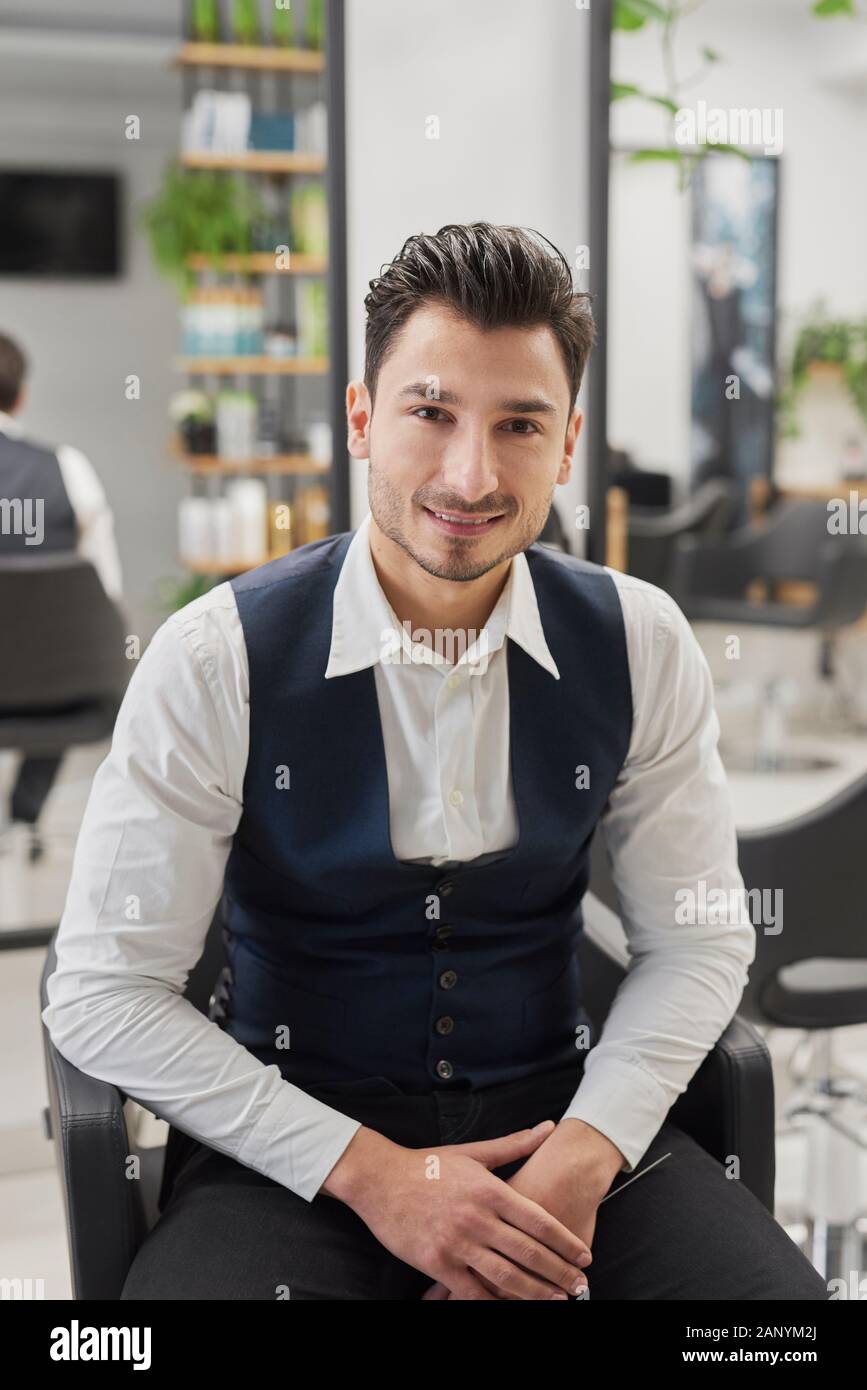 Portrait of smiling male customer assis dans un salon de coiffure Banque D'Images