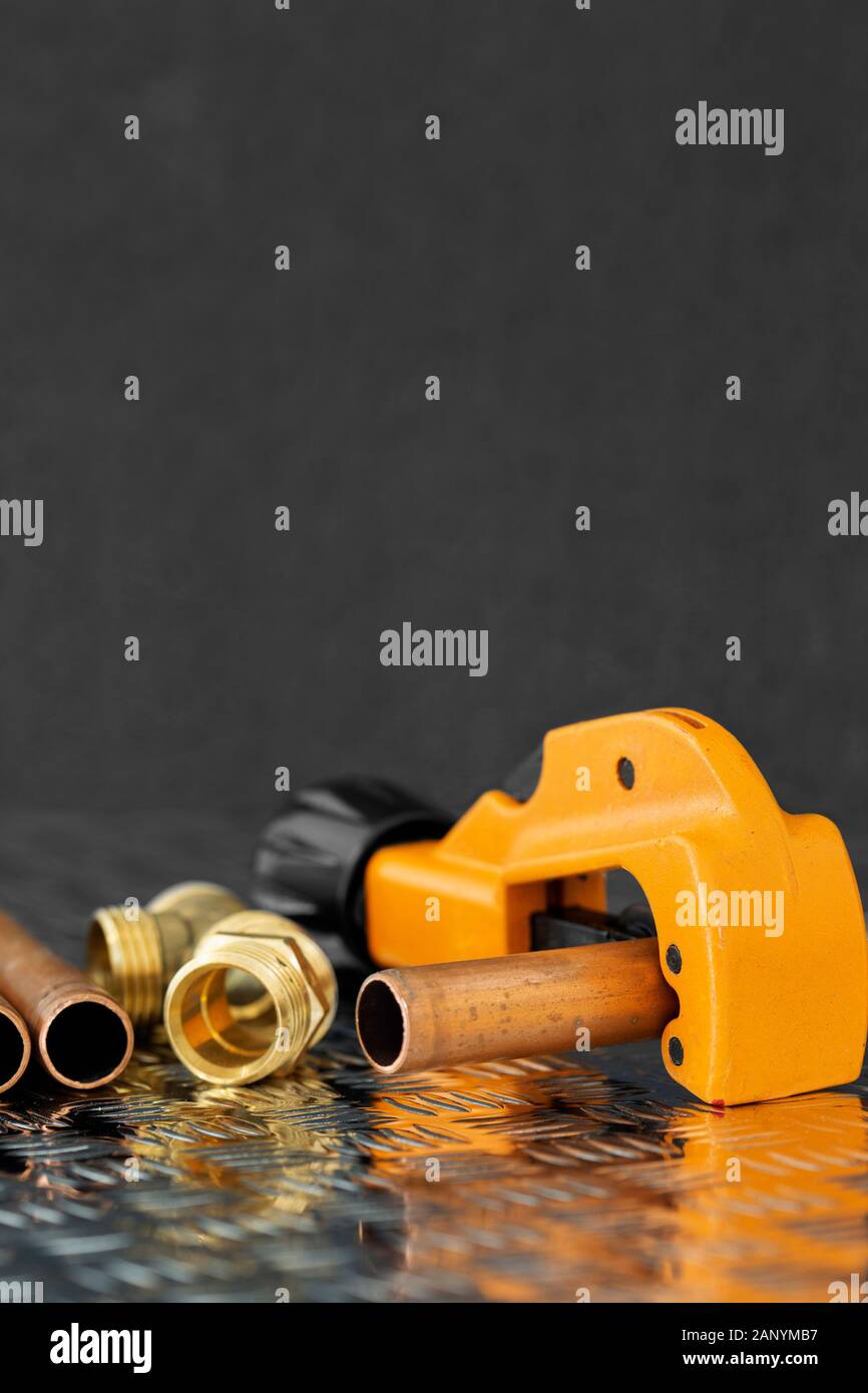 Coupe de tuyaux en cuivre et à la plomberie des connecteurs situés sur une surface en acier checker plate. L'outil et de pièces de rechange de plomberie Banque D'Images