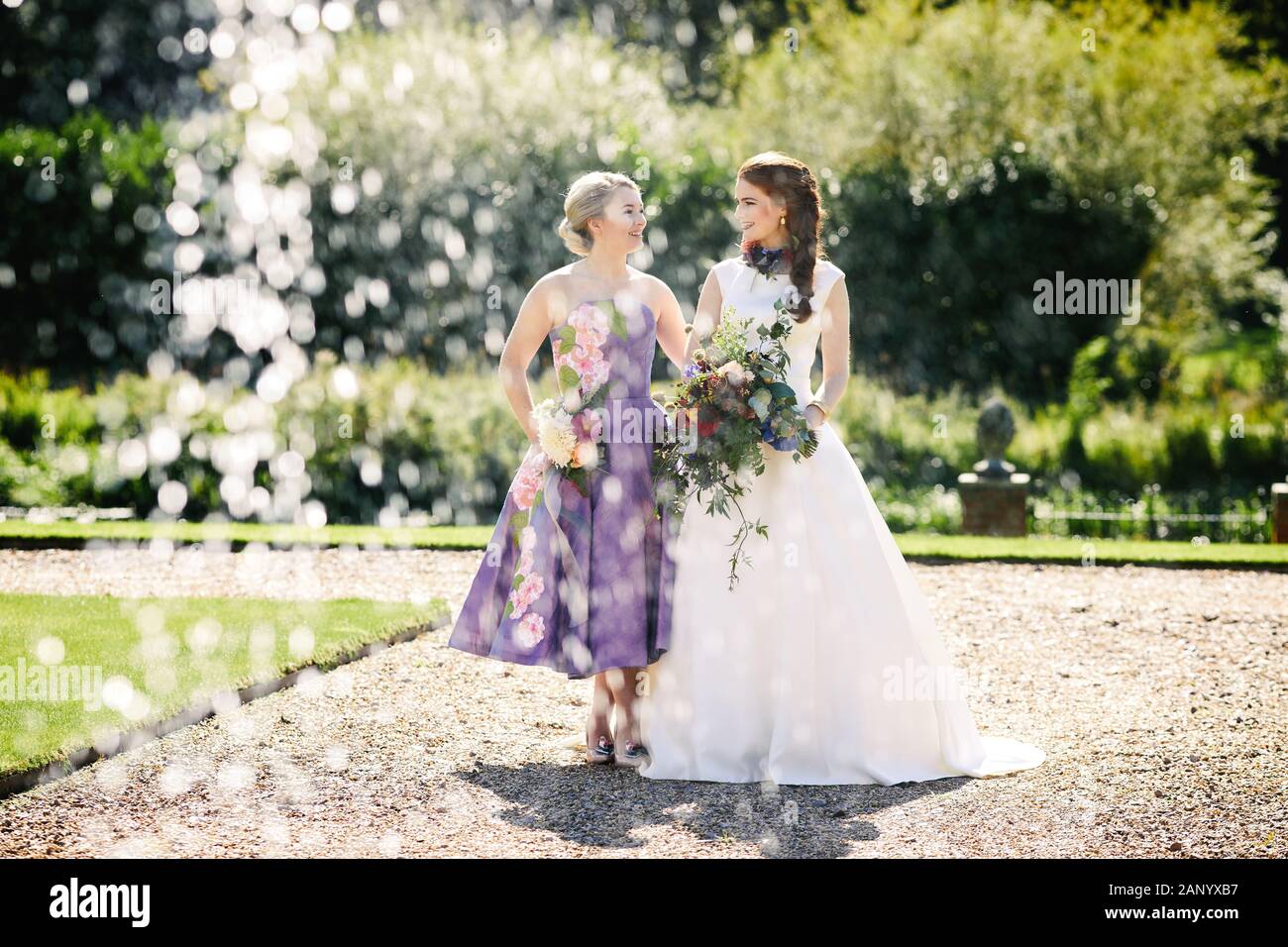 Mariée et femme de chambre dans une robe de mariage ivoire et robe de  demoiselle violette Photo Stock - Alamy