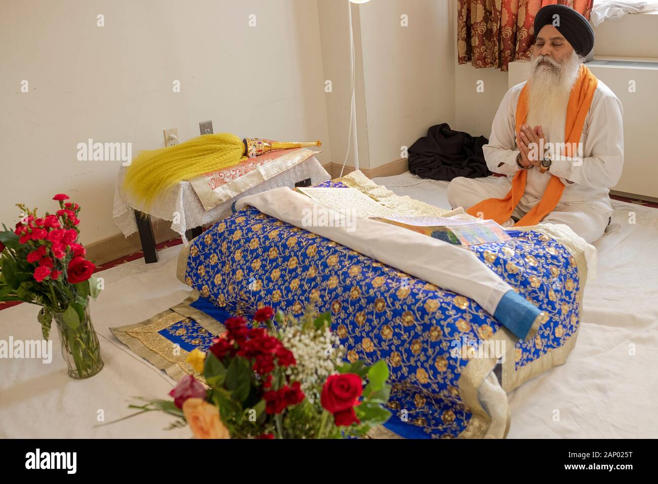 Un prêtre sikh assis lit à partir de la Sainte Écriture, le Gugru Granth Sahib. Dans un temple à Richmond Hill, Queens, New York. Banque D'Images