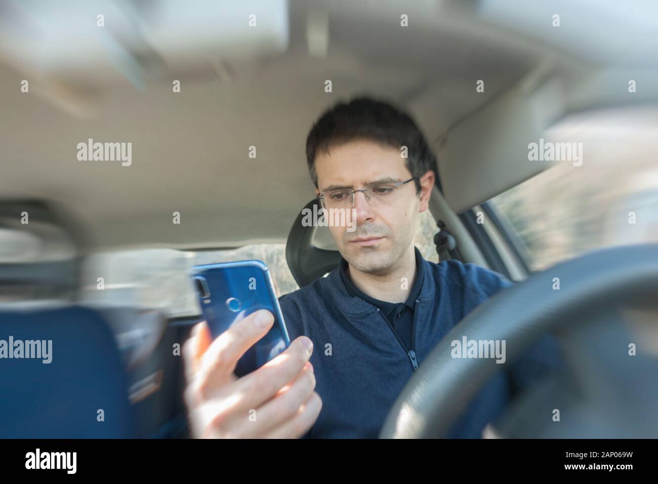 L'homme utilise en roulant smartphone voiture. La conduite dangereuse et de comportement inconscient concept. Banque D'Images
