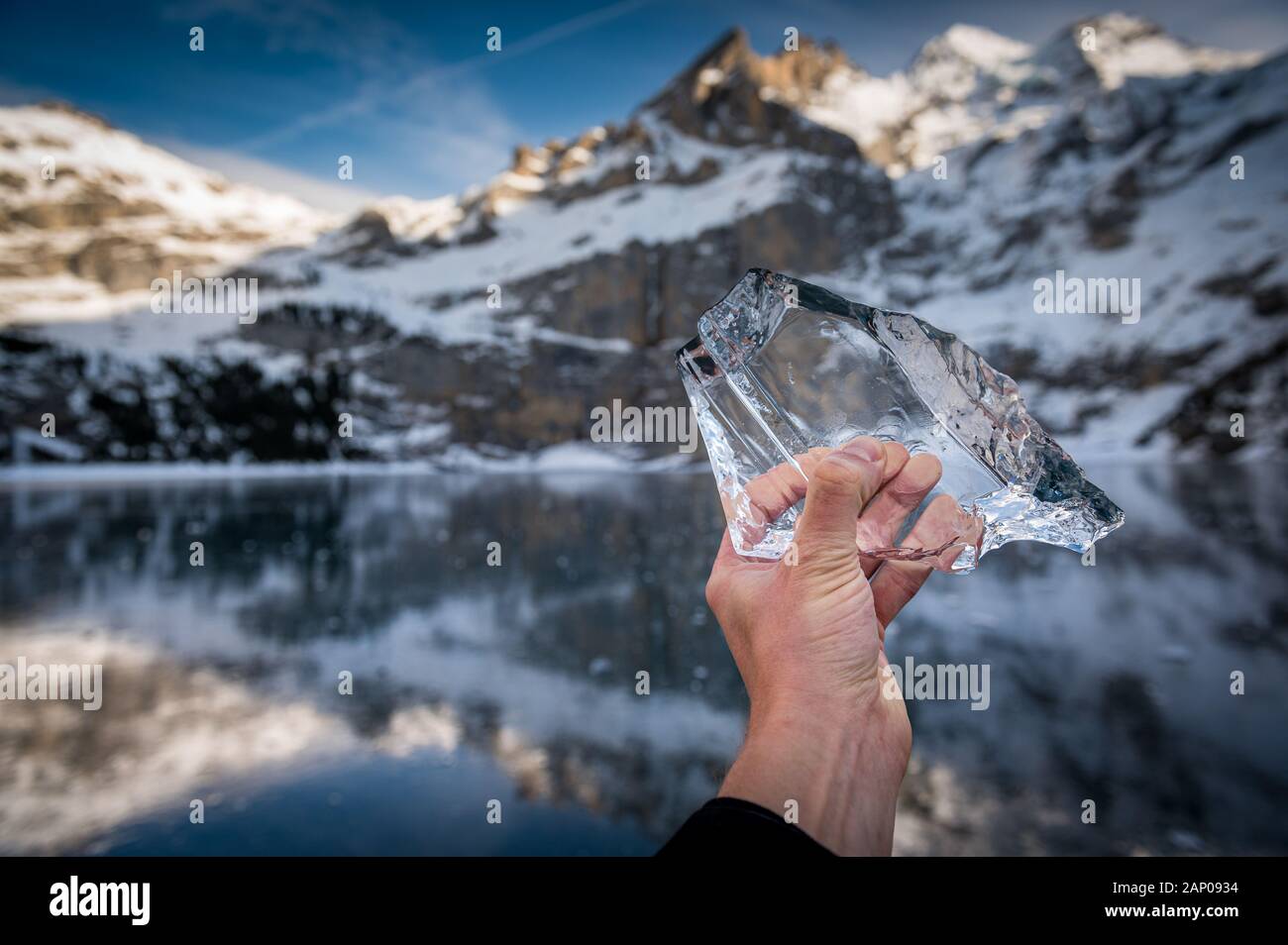 Main tenant une belle partie de la glace sur le lac gelé avec la réflexion et l'Oeschinensee Blümlisalp Montagnes à Berner Oberland Banque D'Images