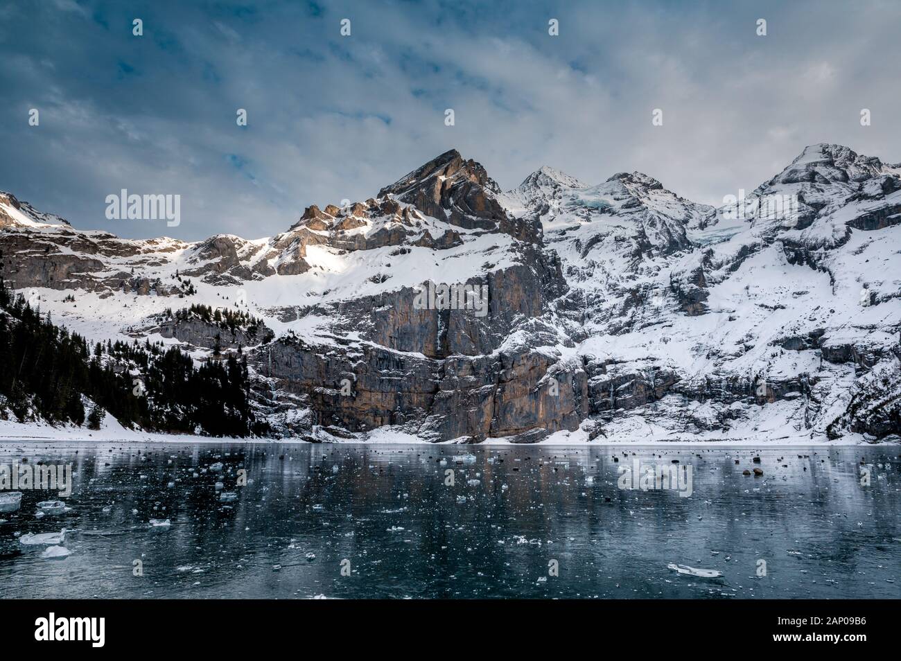 Des bulles sur le lac gelé l'Oeschinensee avec reflet de la Blümlisalp montagnes dans les Alpes Suisses Banque D'Images