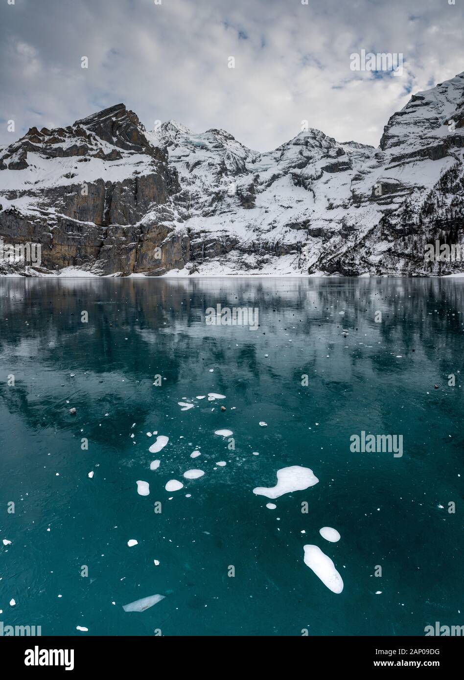 Des bulles sur le lac gelé l'Oeschinensee avec reflet de la Blümlisalp montagnes dans les Alpes Suisses Banque D'Images