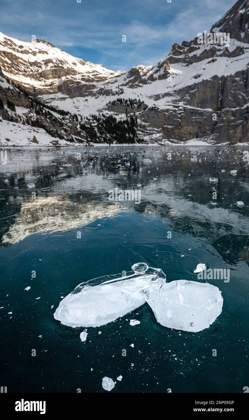 Blocs de glace sur le lac gelé l'Oeschinensee avec reflet de la Blümlisalp montagnes dans les Alpes Suisses Banque D'Images