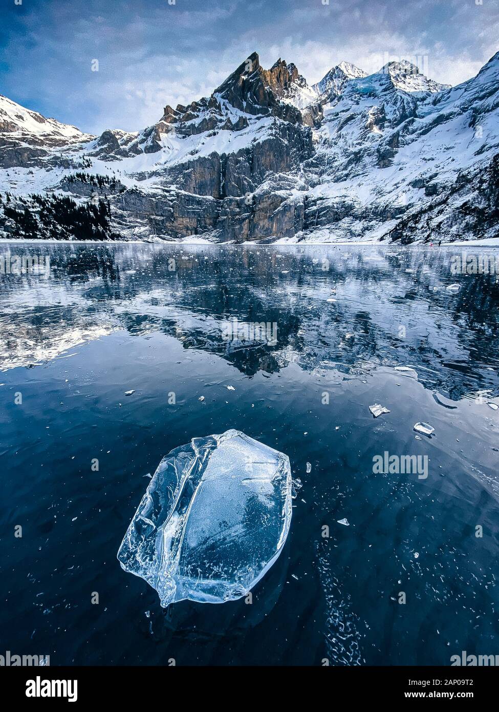 Beaufiful Effacer bloc de glace sur un lac gelé l'Oeschinensee avec réflexion et Blümlisalp montagnes dans les Alpes Bernoises Banque D'Images