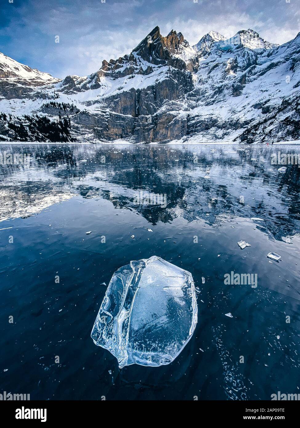 Beaufiful Effacer bloc de glace sur un lac gelé l'Oeschinensee avec réflexion et Blümlisalp montagnes dans les Alpes Bernoises Banque D'Images