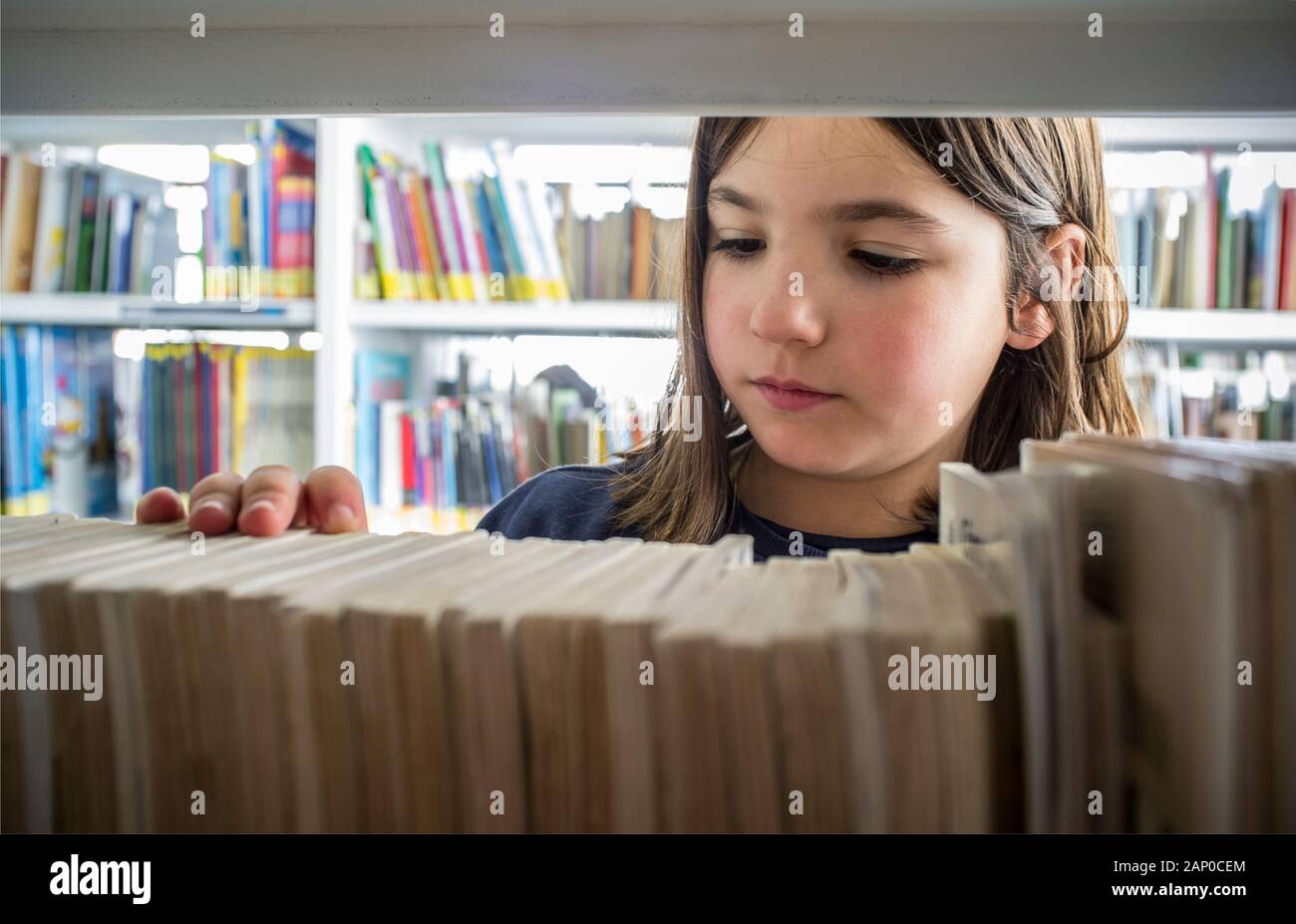Jeune fille la sélection de livres de la bibliothèque étagère. La créativité et l'imagination des enfants concept. Banque D'Images