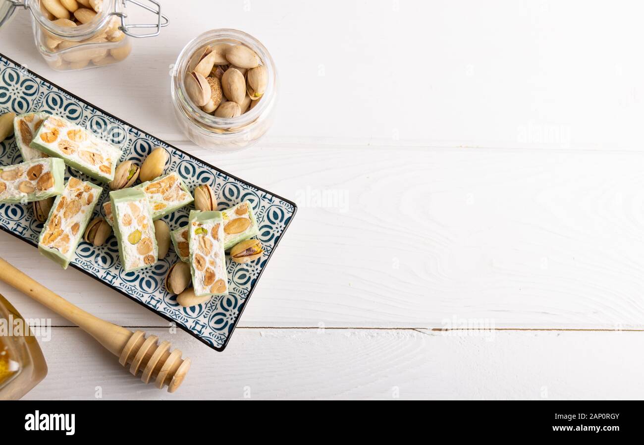 Nougat bio faites avec du miel, pistache, noisette, noix et amandes, sur un fond blanc. Banque D'Images