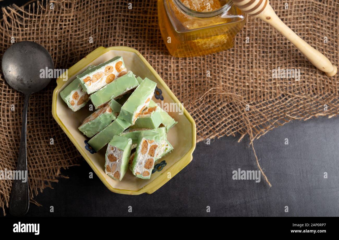 Nougat bio faites avec du miel, pistache, noisette, noix et amandes, sur un fond sombre. rustique Banque D'Images