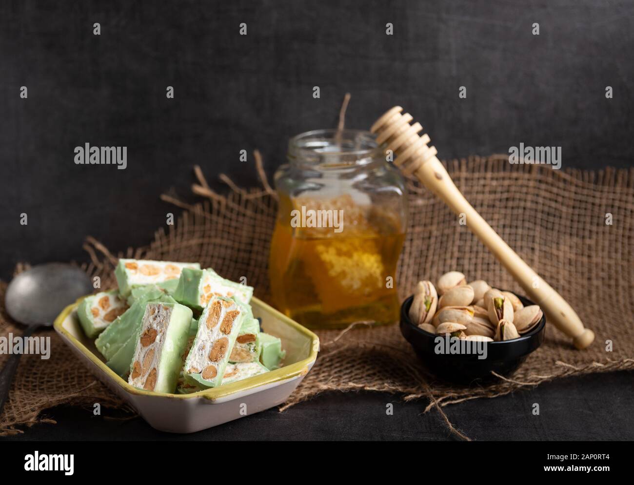 Nougat bio faites avec du miel, pistache, noisette, noix et amandes, sur un fond sombre. rustique Banque D'Images