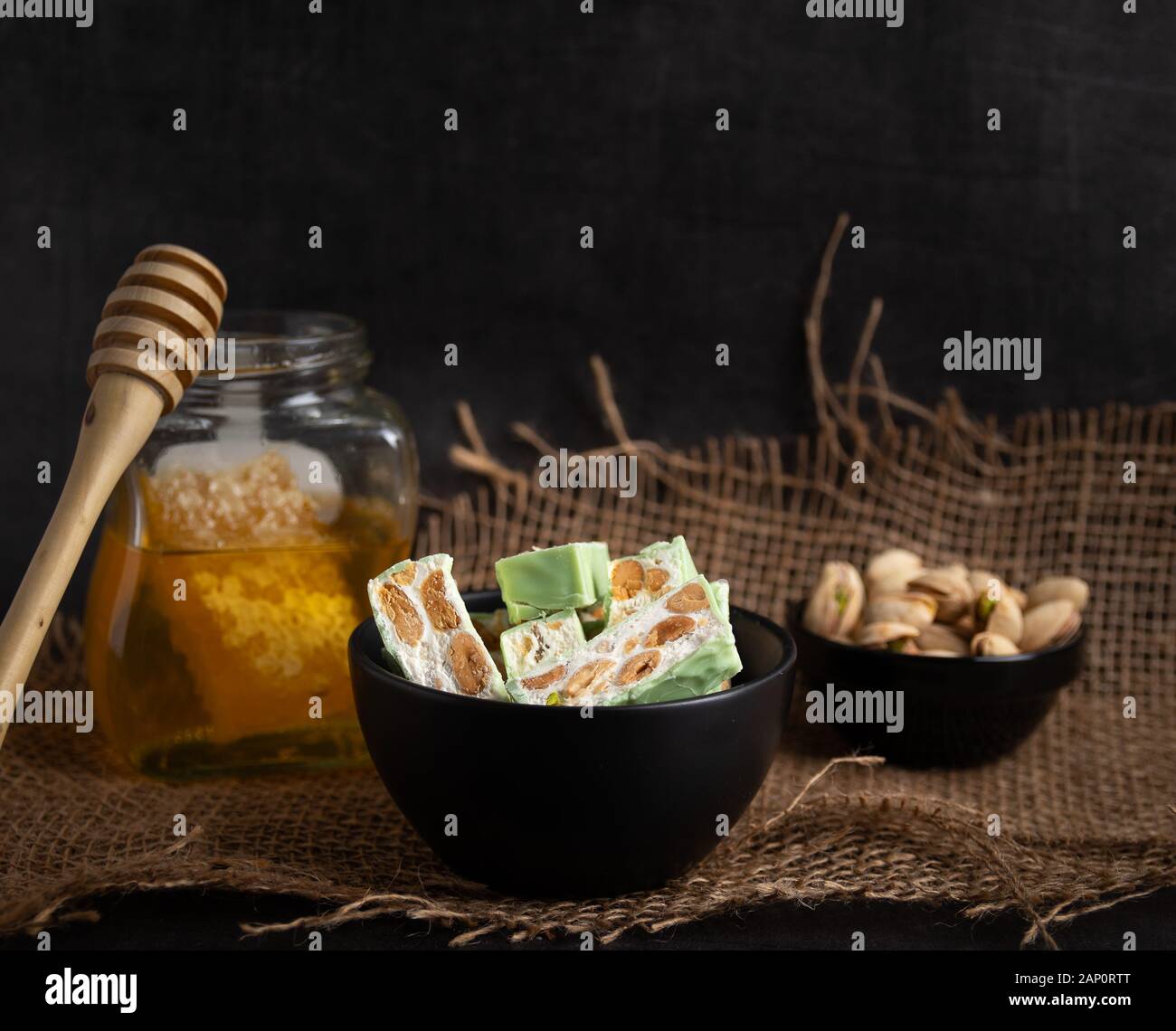 Nougat bio faites avec du miel, pistache, noisette, noix et amandes, sur un fond sombre. rustique Banque D'Images