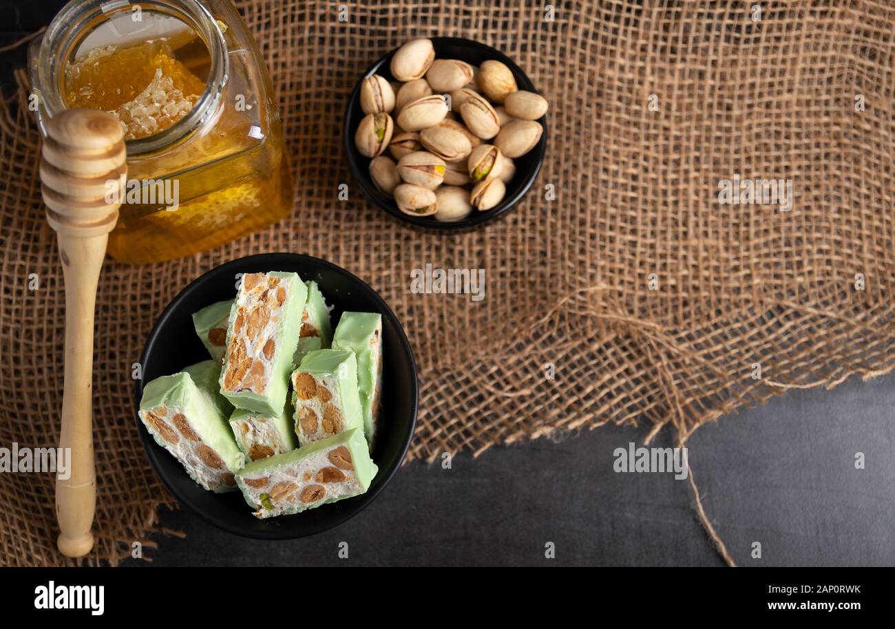 Nougat bio faites avec du miel, pistache, noisette, noix et amandes, sur un fond sombre. rustique Banque D'Images