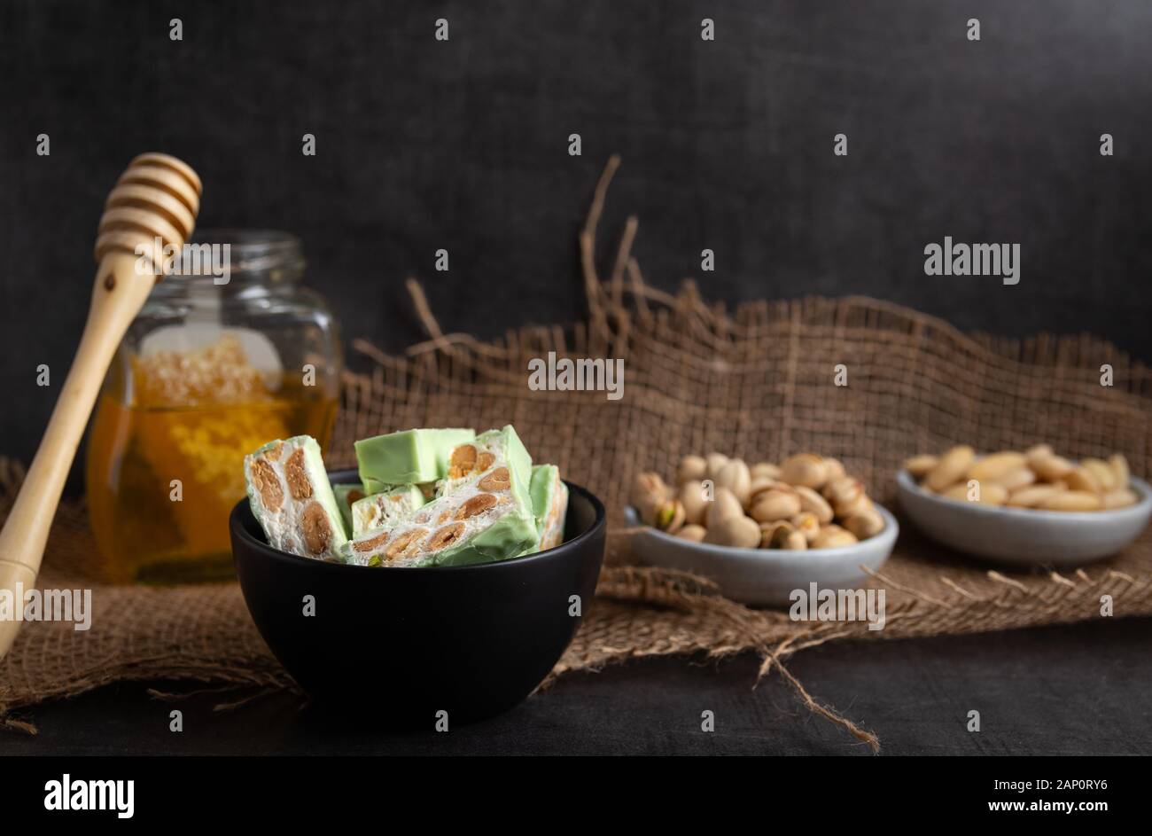 Nougat bio faites avec du miel, pistache, noisette, noix et amandes, sur un fond sombre. rustique Banque D'Images