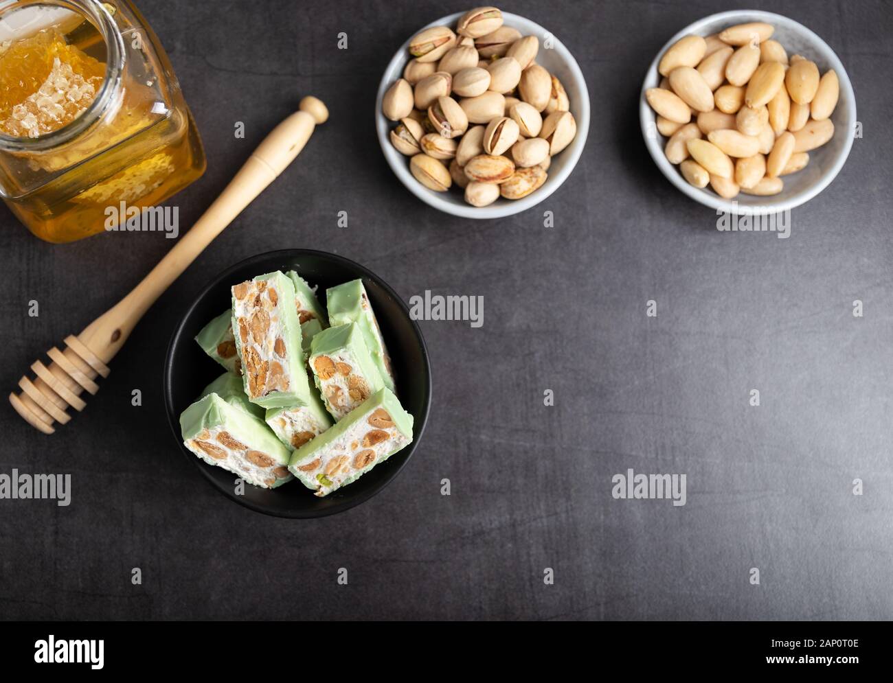 Nougat bio faites avec du miel, pistache, noisette, noix et amandes, sur un fond sombre. rustique Banque D'Images