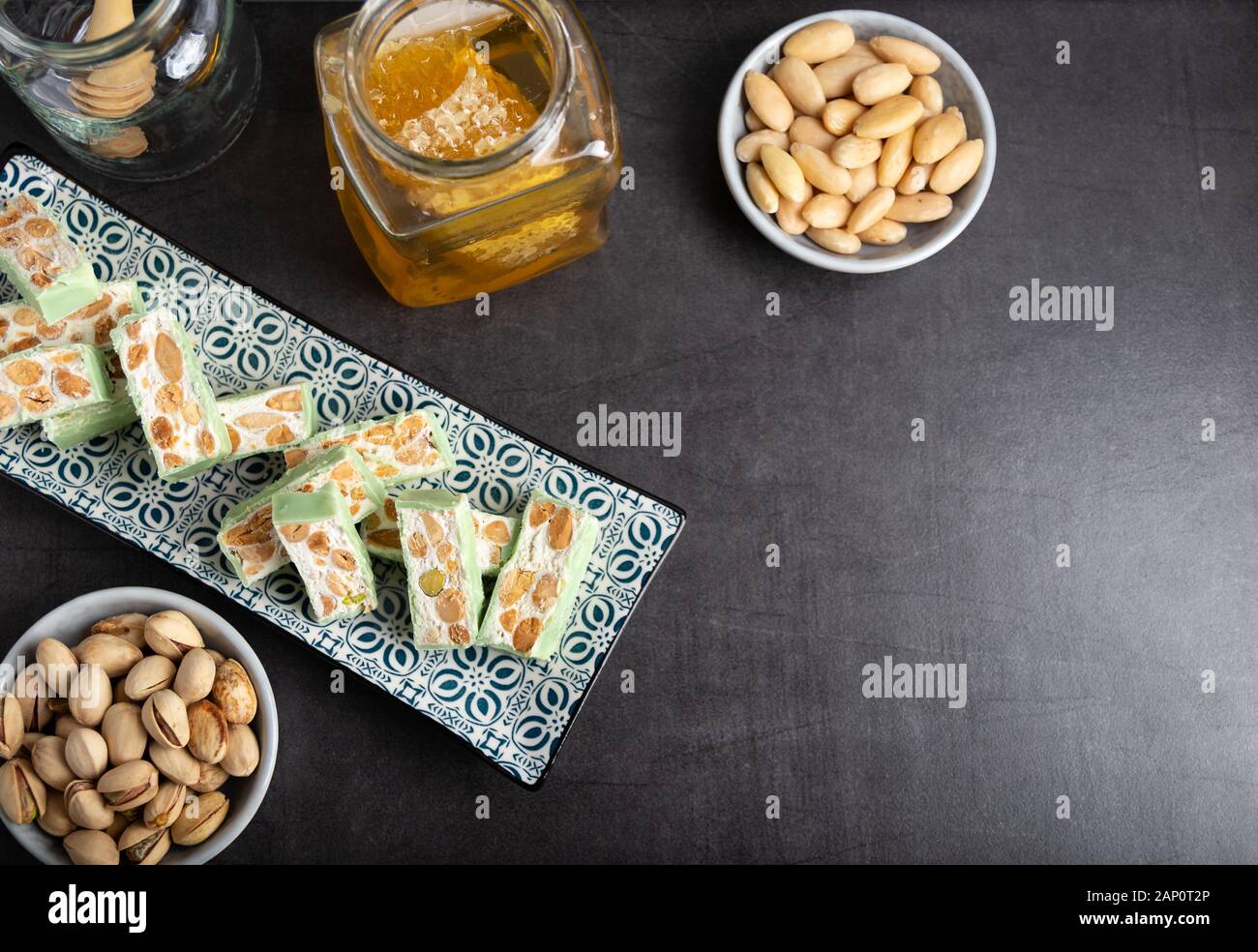 Nougat bio faites avec du miel, pistache, noisette, noix et amandes, sur un fond sombre. rustique Banque D'Images
