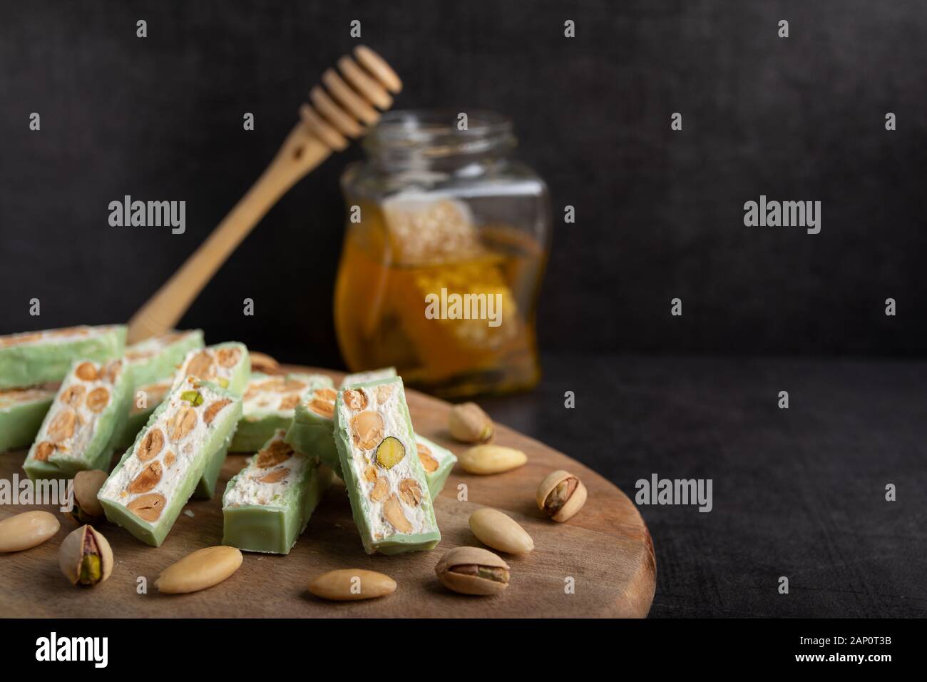 Nougat bio faites avec du miel, pistache, noisette, noix et amandes, sur un fond sombre. rustique Banque D'Images