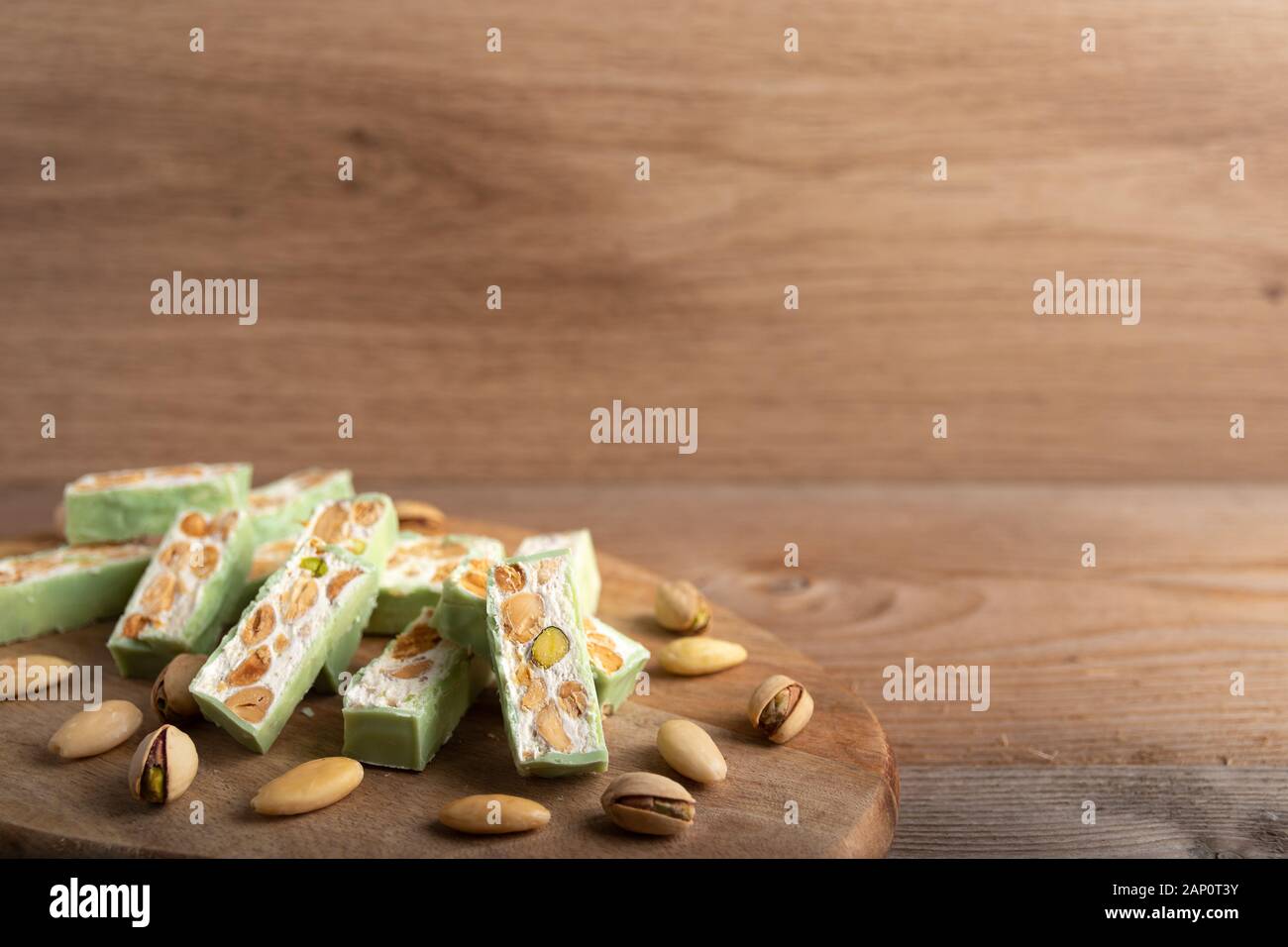 Nougat bio faites avec du miel, pistache, noisette, amande et noix sur une table en bois en arrière-plan. Banque D'Images