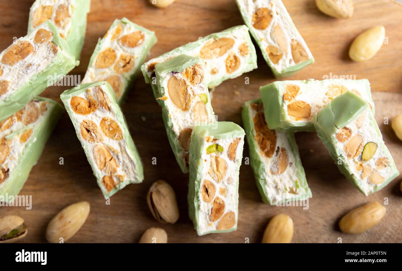 Nougat bio faites avec du miel, pistache, noisette, amande et noix sur une table en bois en arrière-plan. Banque D'Images