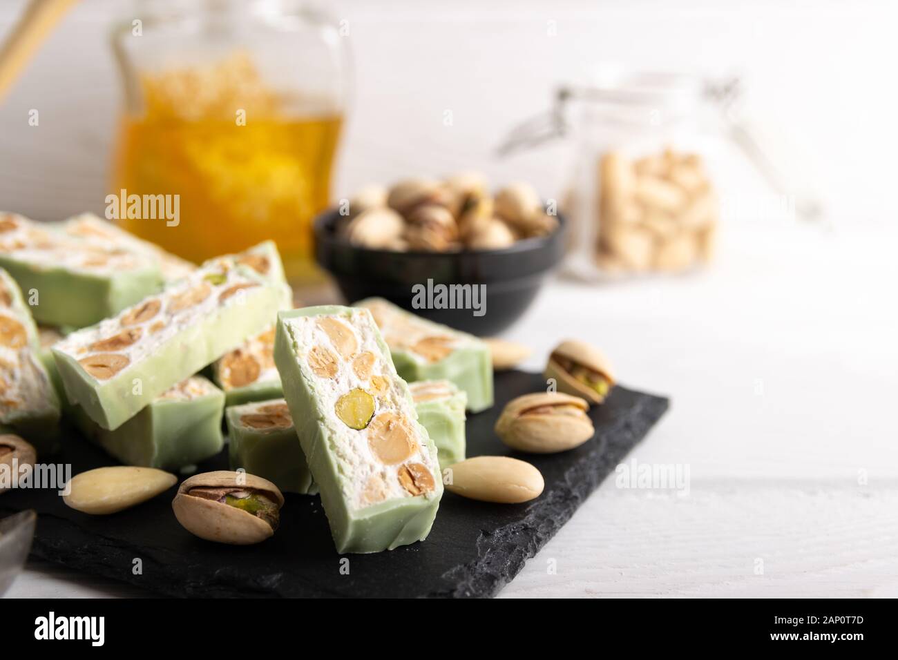 Nougat bio faites avec du miel, pistache, noisette, noix et amandes, sur un fond blanc. Banque D'Images