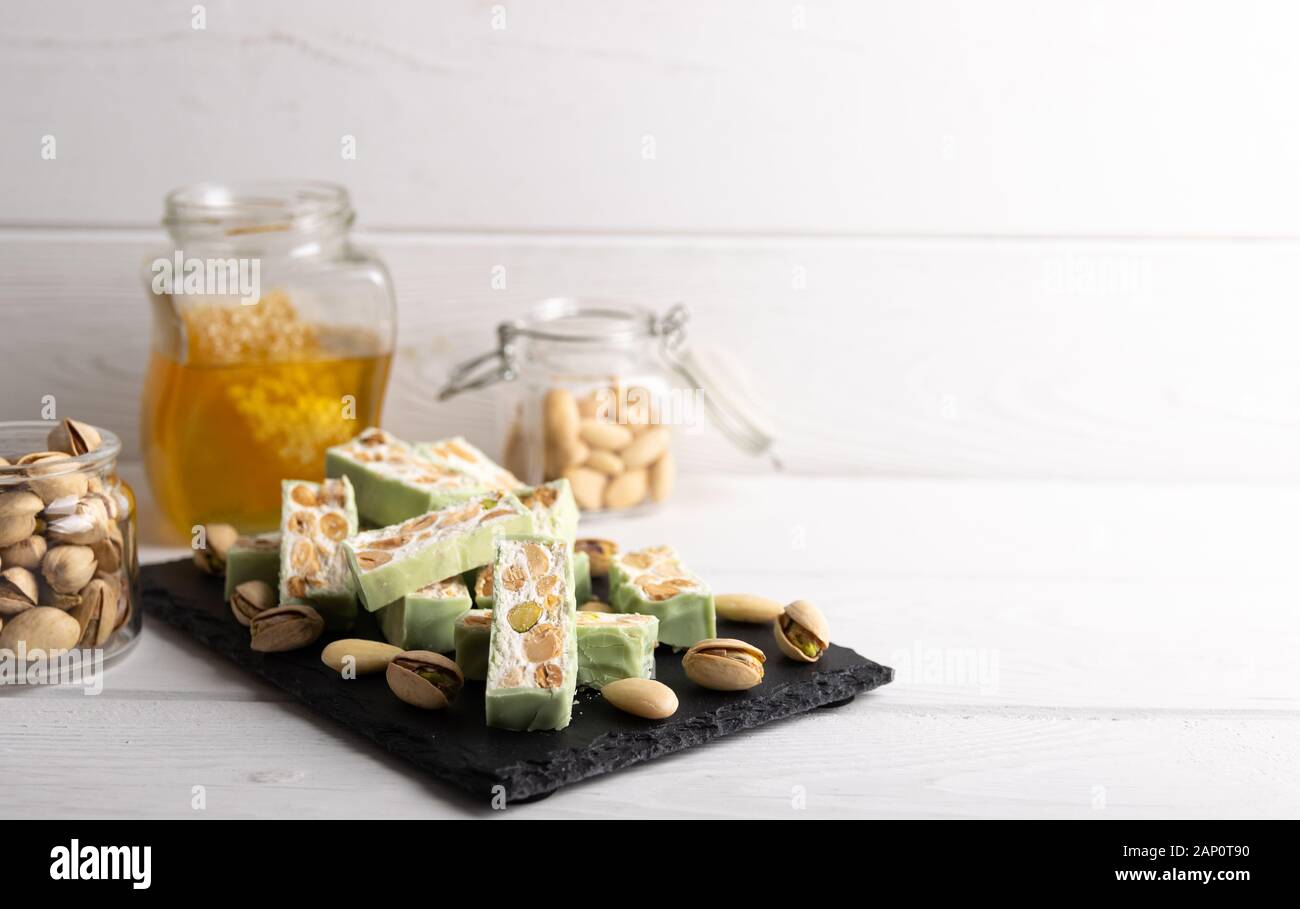 Nougat bio faites avec du miel, pistache, noisette, noix et amandes, sur un fond blanc. Banque D'Images