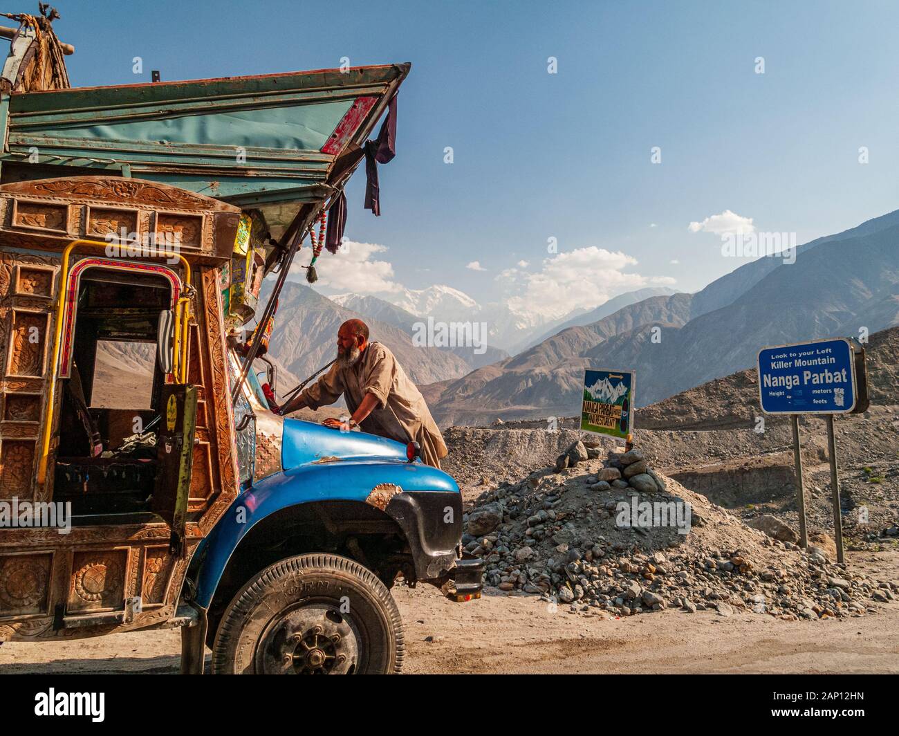 Un conducteur nettoie son camion coloré et peint, conduisant sur les routes poussiéreuses de l'autoroute Karakorum Banque D'Images