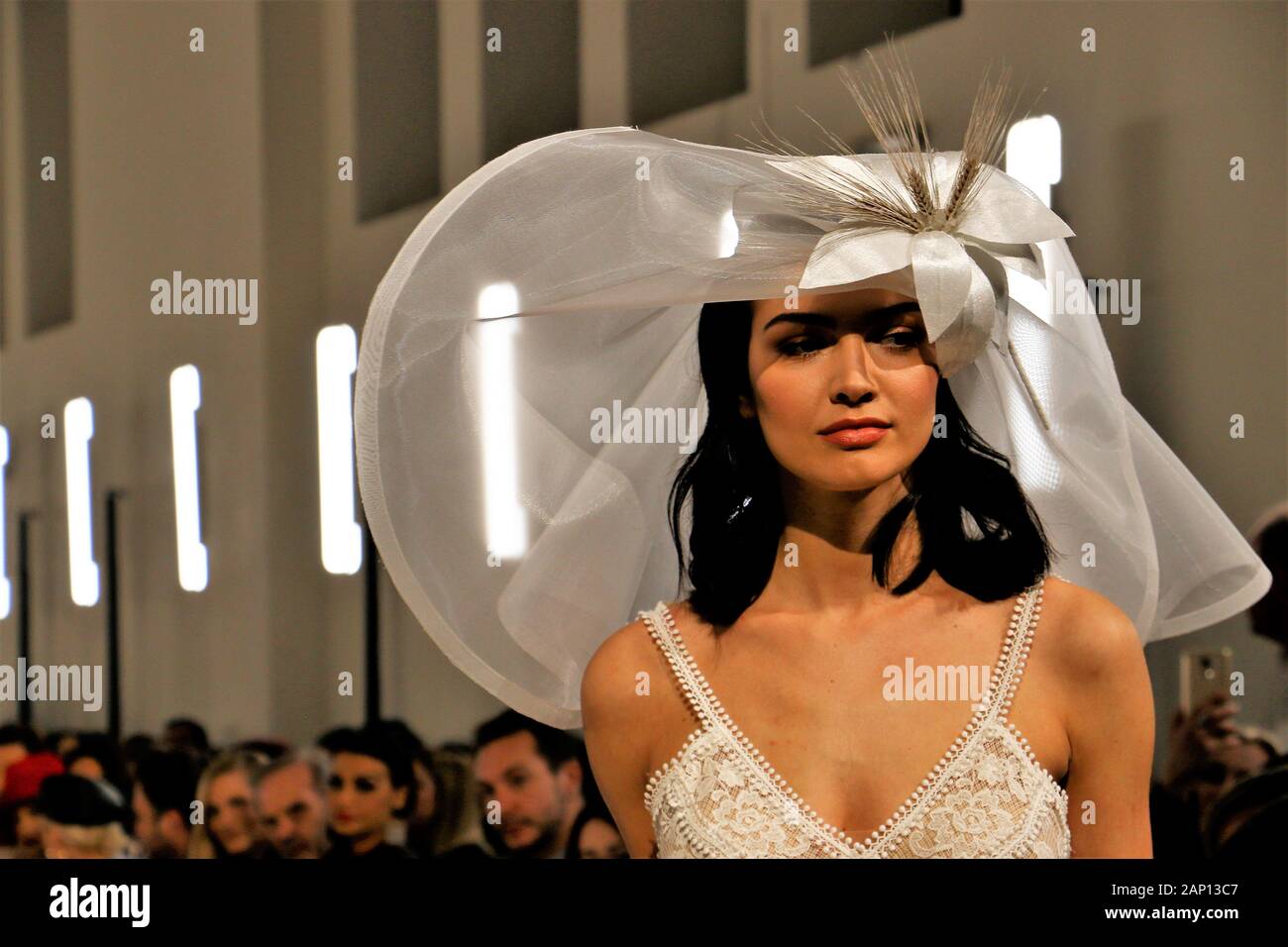 Le modèle grec Keisi Miziou dans une robe de mariage de la styliste grecque Theodorou Stalo avec un beau grand chapeau au cours de la deuxième journée de l'événement.Trois femmes designers ont uni leurs forces pour présenter leurs créations de mariage à la suite nuptiale d'Athènes la semaine de la mode, Megaron Zappeion. Banque D'Images