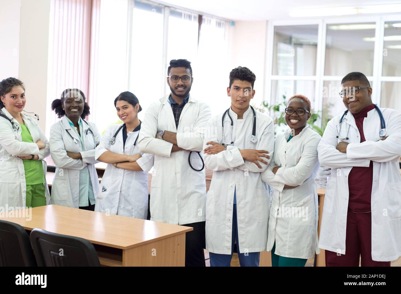 Les étudiants en médecine, médecins, race mixte. Une équipe de jeunes gens en blouse blanche posant dans le couloir de l'hôpital Banque D'Images