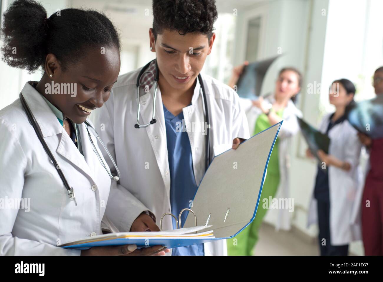 Portrait de médecins, de race mixte. Une fille noire, avec un mec mexicain, en blouse blanche, avec les stéthoscopes, tient des documents médicaux, une consultation, une Banque D'Images