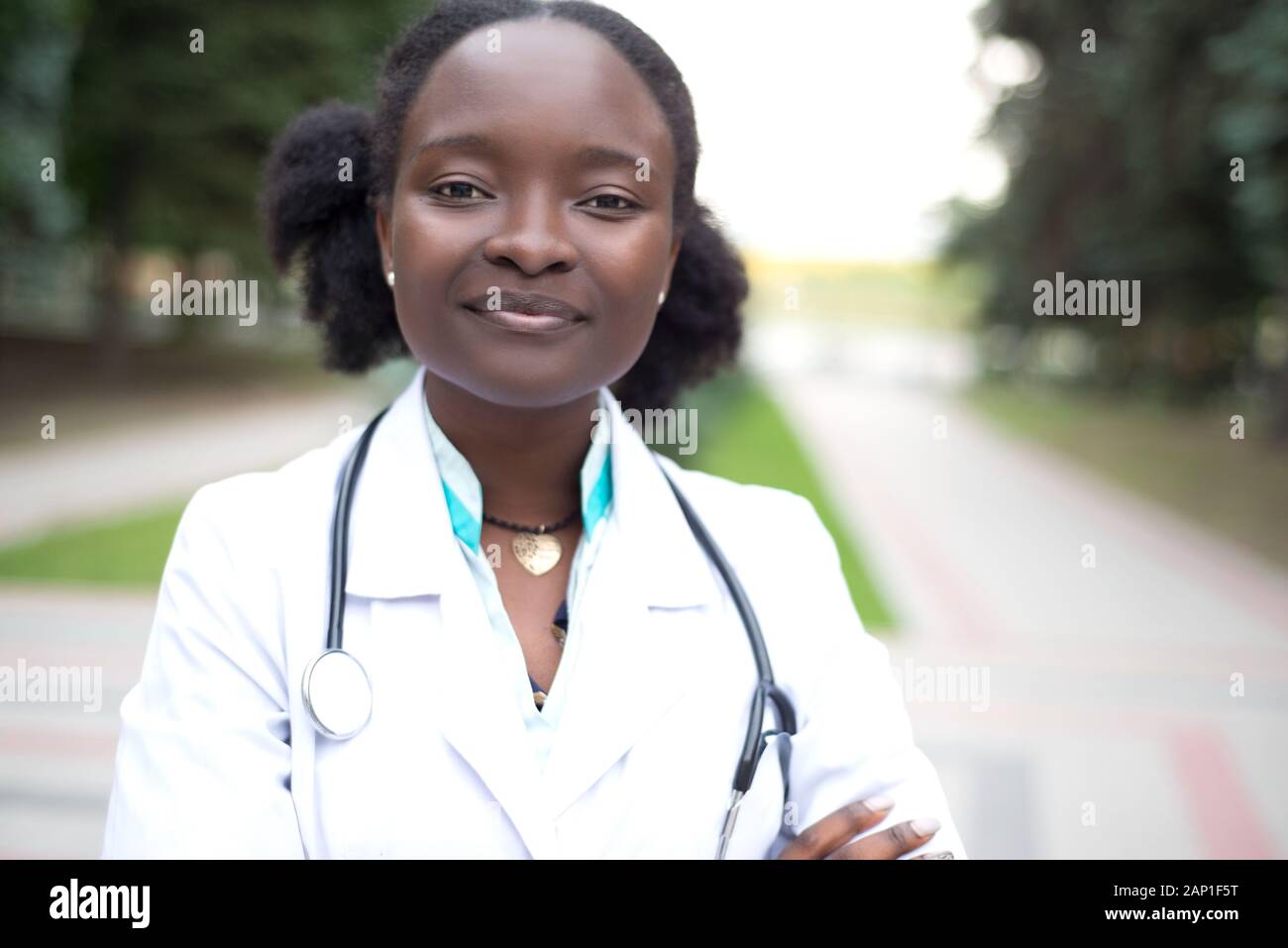 Portrait d'une belle jeune fille africaine, médecin. Femme en blouse blanche avec un stéthoscope en souriant. En plein air Banque D'Images