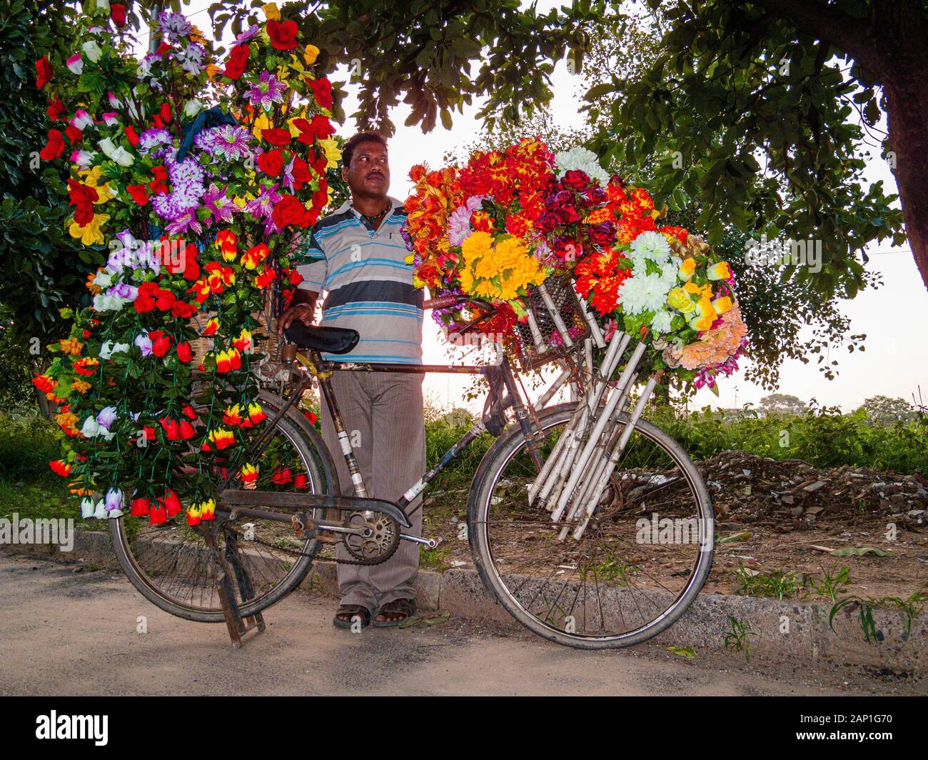 Un vendeur vend des fleurs artificielles à partir d'un magasin de vélos Banque D'Images