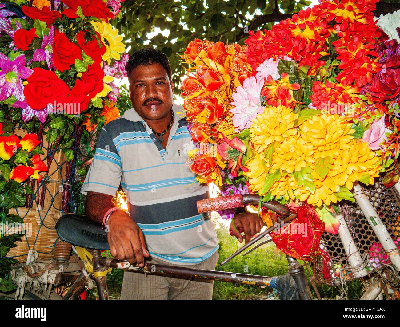Un vendeur vend des fleurs artificielles à partir d'un magasin de vélos Banque D'Images