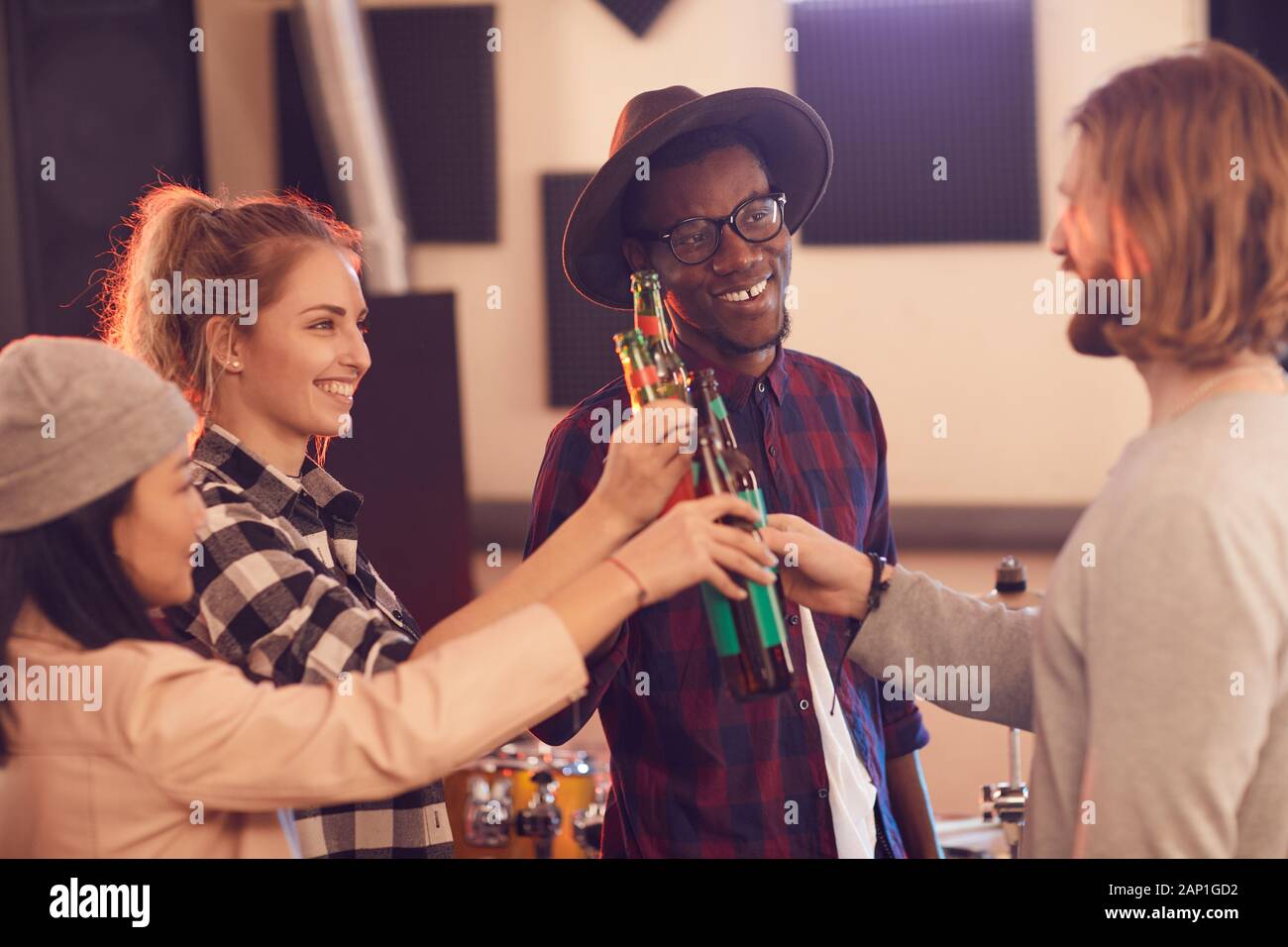 Groupe multi-ethnique des jeunes le grillage avec les bouteilles de bière tout en profitant de répétition en studio de musique Banque D'Images