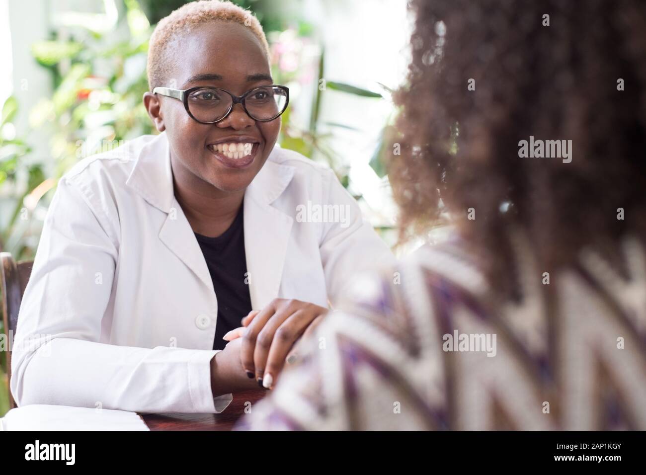 Black woman doctor smiling holding patient mexicain part mixed race jeunes au bureau de médecins Banque D'Images