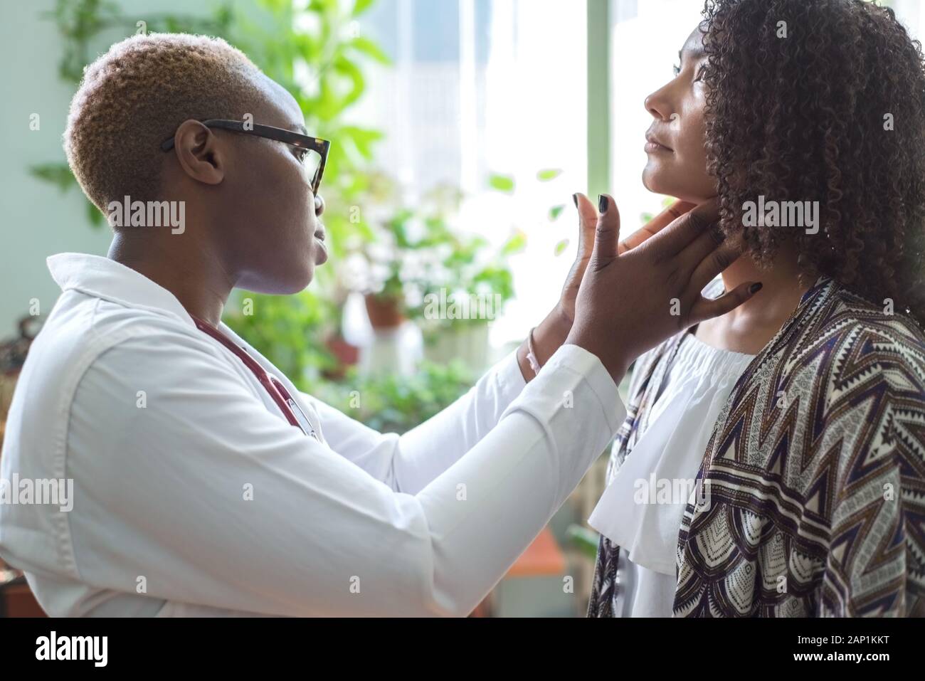 Une fille noire médecin examine un patient mexicain dans un bureau de médecin palpe les ganglions du cou Banque D'Images