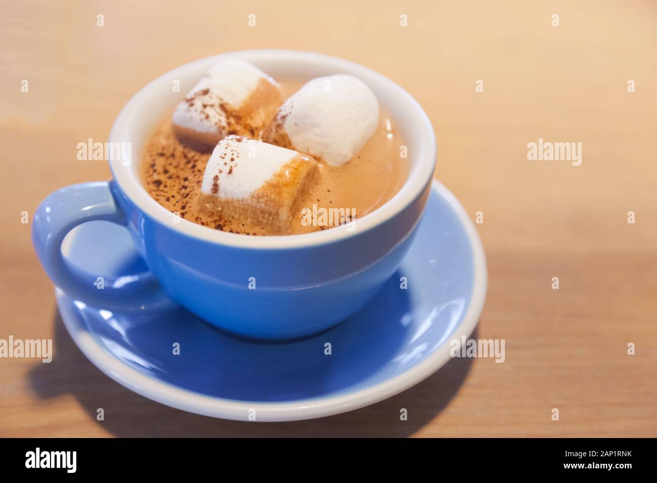 Boire du chocolat chaud surmonté d'une mousse de lait Latte avec de la guimauve dans la tasse de porcelaine céramique bleu sur fond de table en bois. Moment de détente en bonne santé avec d Banque D'Images