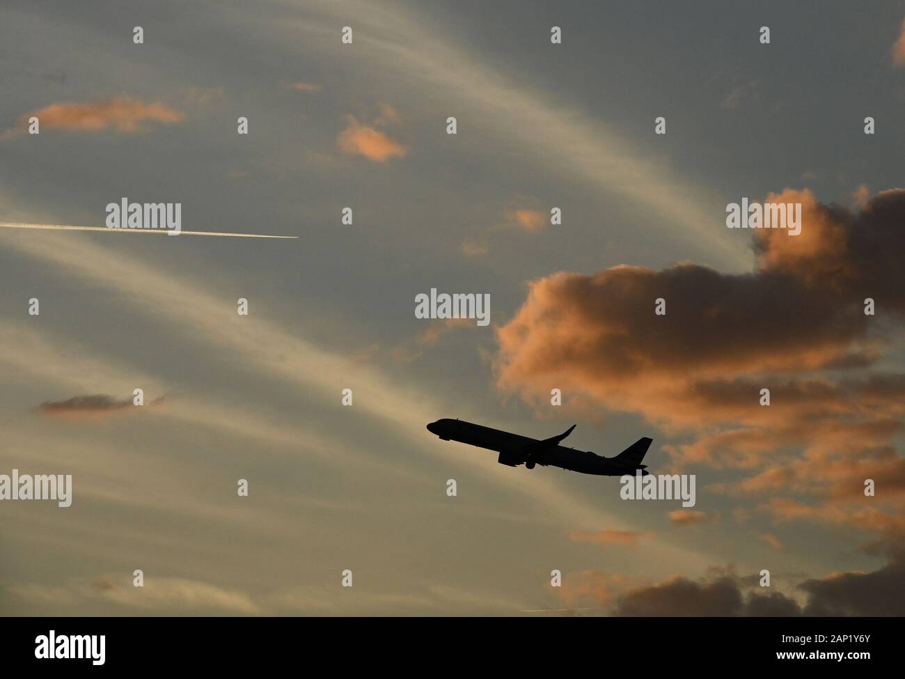 Un avion commercial part à l'aéroport international d'Orlando au coucher du soleil alors que le contrail d'un autre avion est en arrière-plan. Banque D'Images