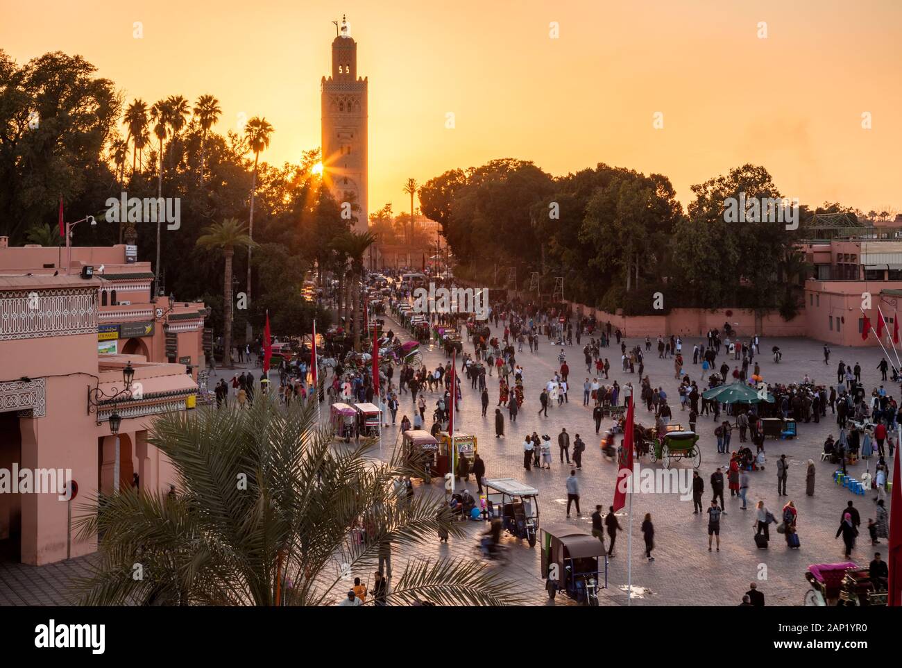 Le minaret de la mosquée de la Kasbah à l'animation de la place Jemaa el-Fna au coucher du soleil à partir d'un patio à Marrakech, Maroc. Marrakesh-Safi Banque D'Images