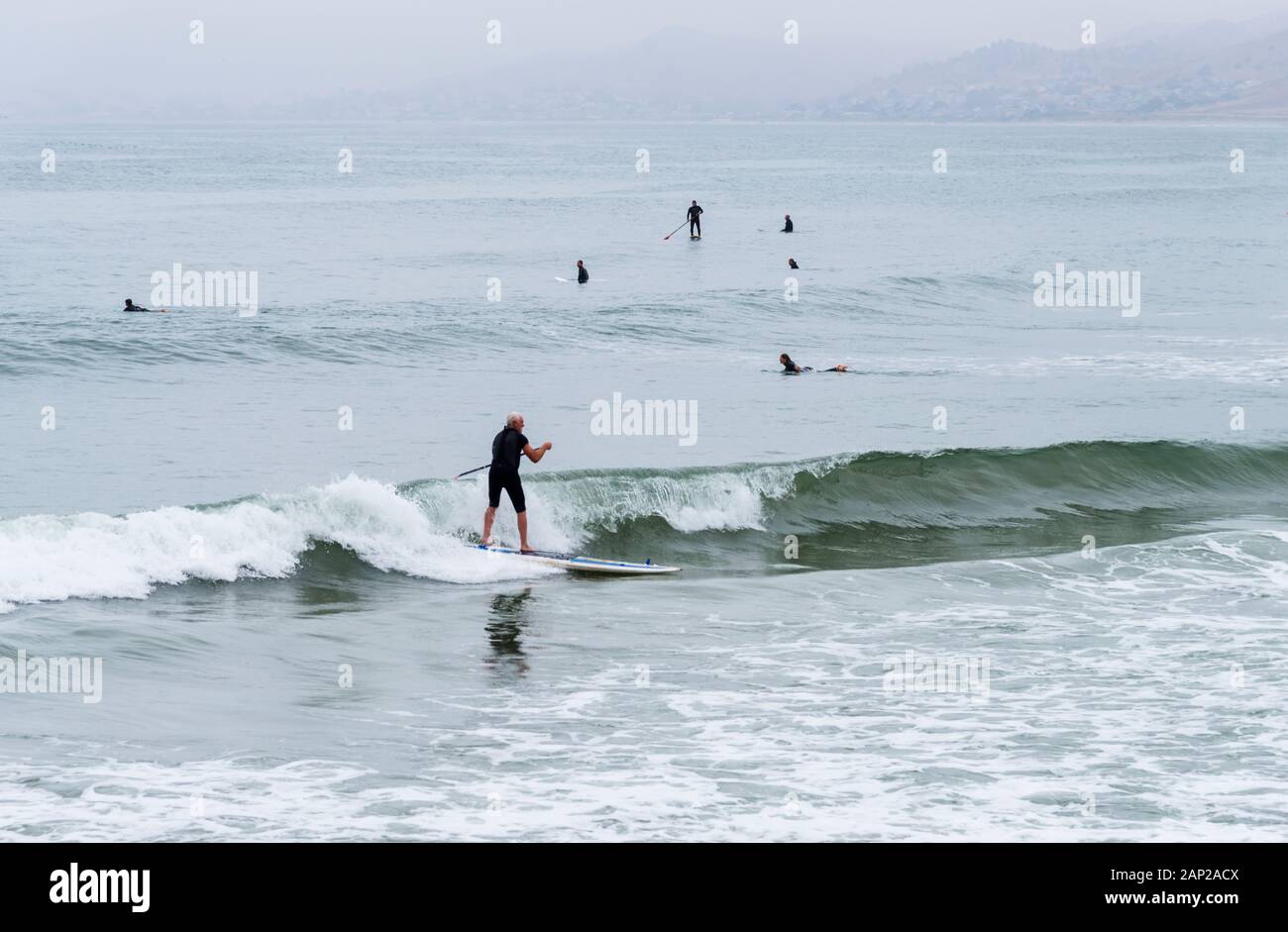 Les surfeurs capturent des vagues viviviviantes du Pacifique à Morro Rock Beach lors d'une matinée estivale surmoulée le long de la côte californienne. Banque D'Images