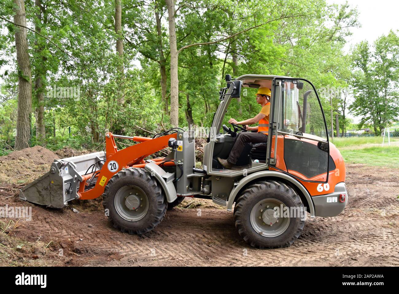 Travailleur de la construction conduit un petit chargeur à roues sur le site de construction Banque D'Images