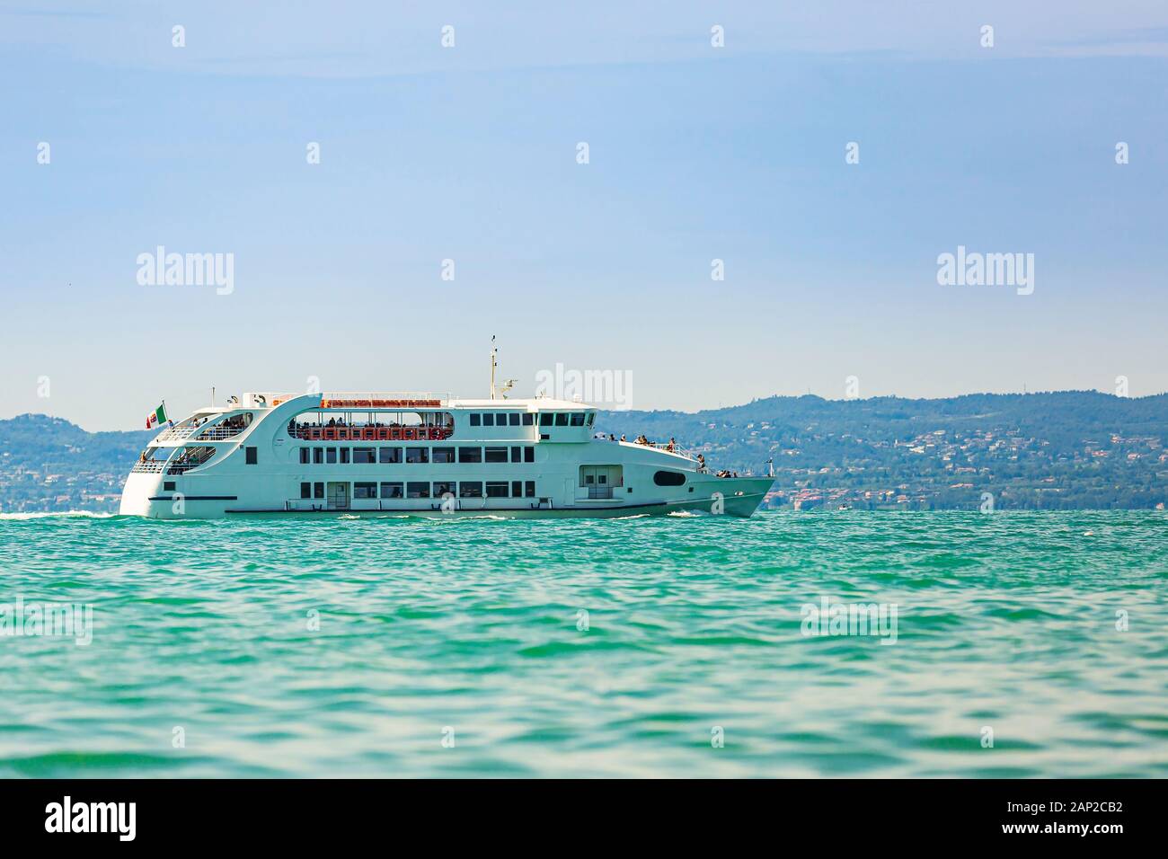 Bateau transportant des touristes sur le lac de Garde. Ciel bleu clair jour d'été. Banque D'Images