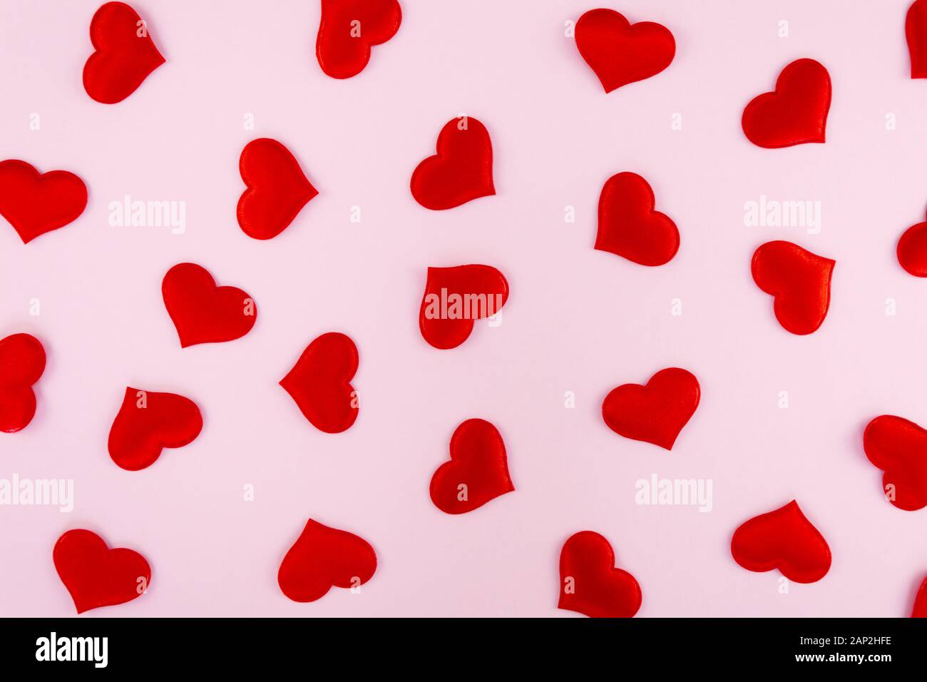Coeurs rouges dispersées sur un fond rose avec de l'espace libre pour le texte Banque D'Images